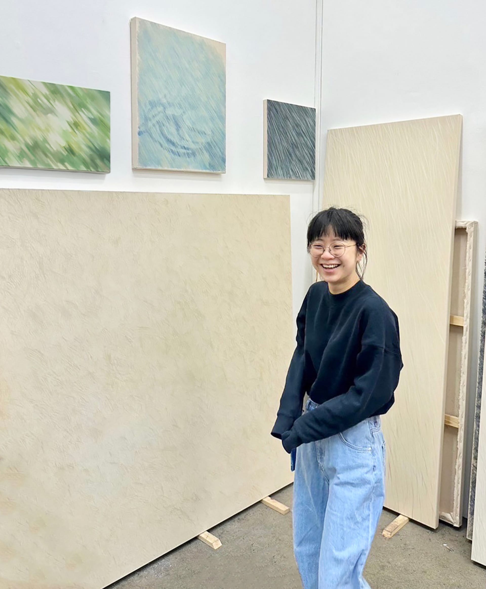 Nai-Jen standing with her paintings in the corner of her studio at RCA