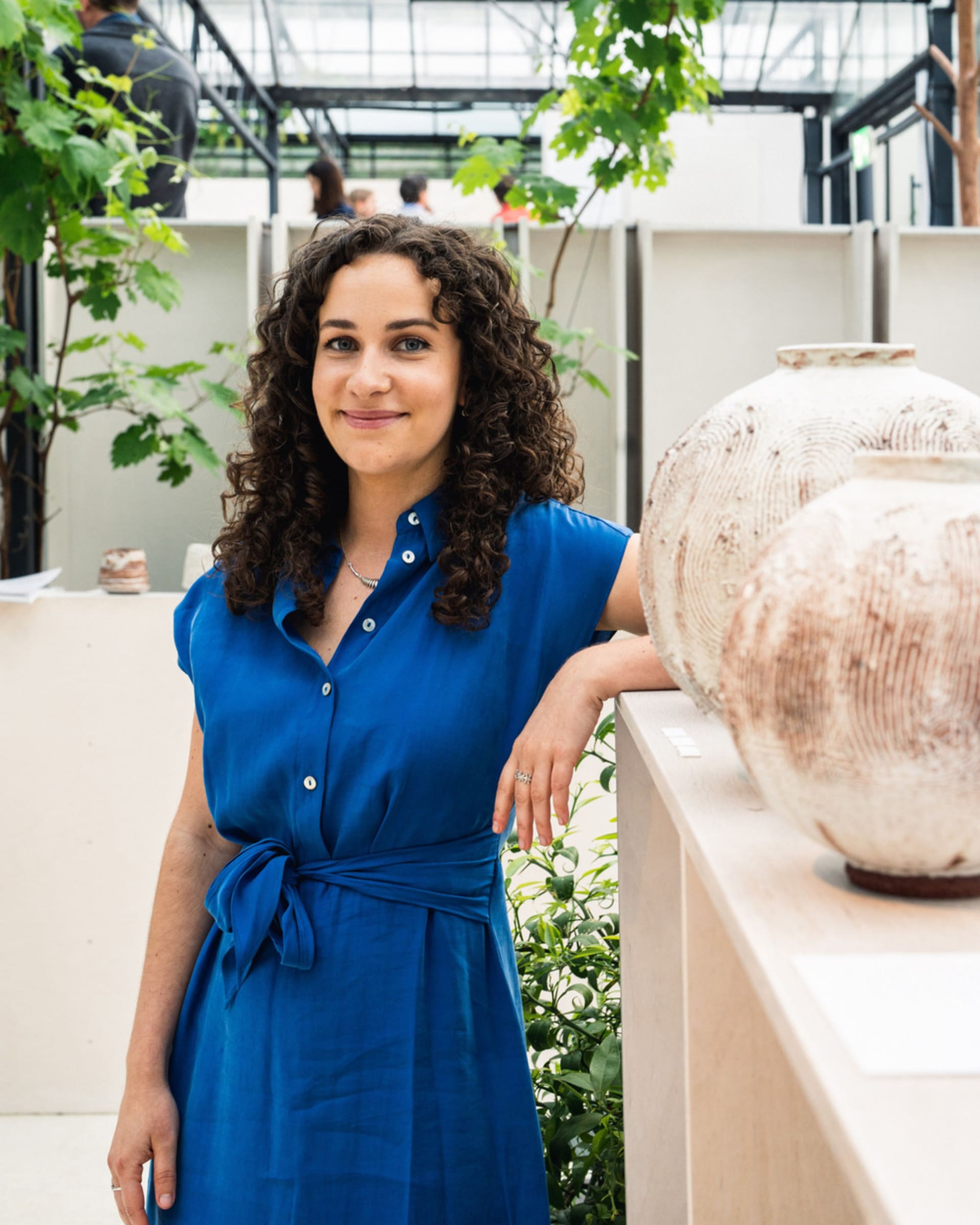 Portrait photograph of Heather Gibson standing by a shelf of moon jars