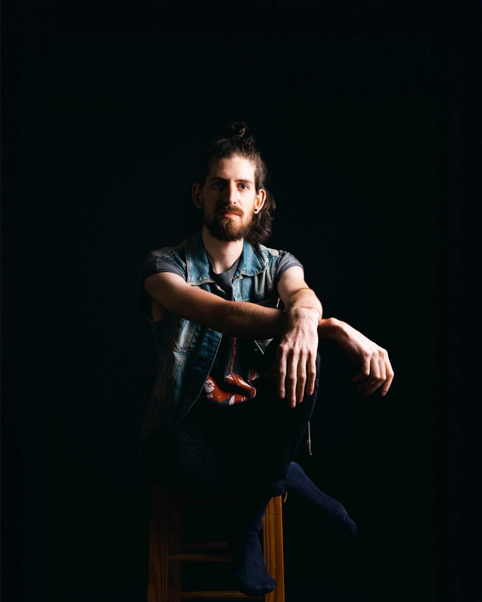 Profile Picture. A man in his twenties sitting on a stool. 