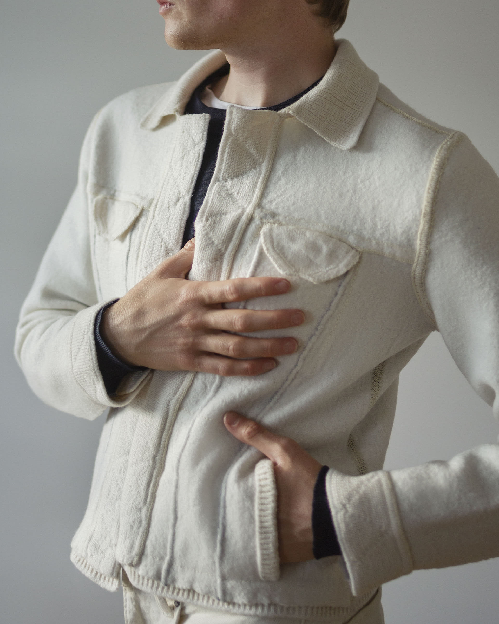 Close up on front of jacket, worn by white male, left hand in pocket, right hand part way down chest