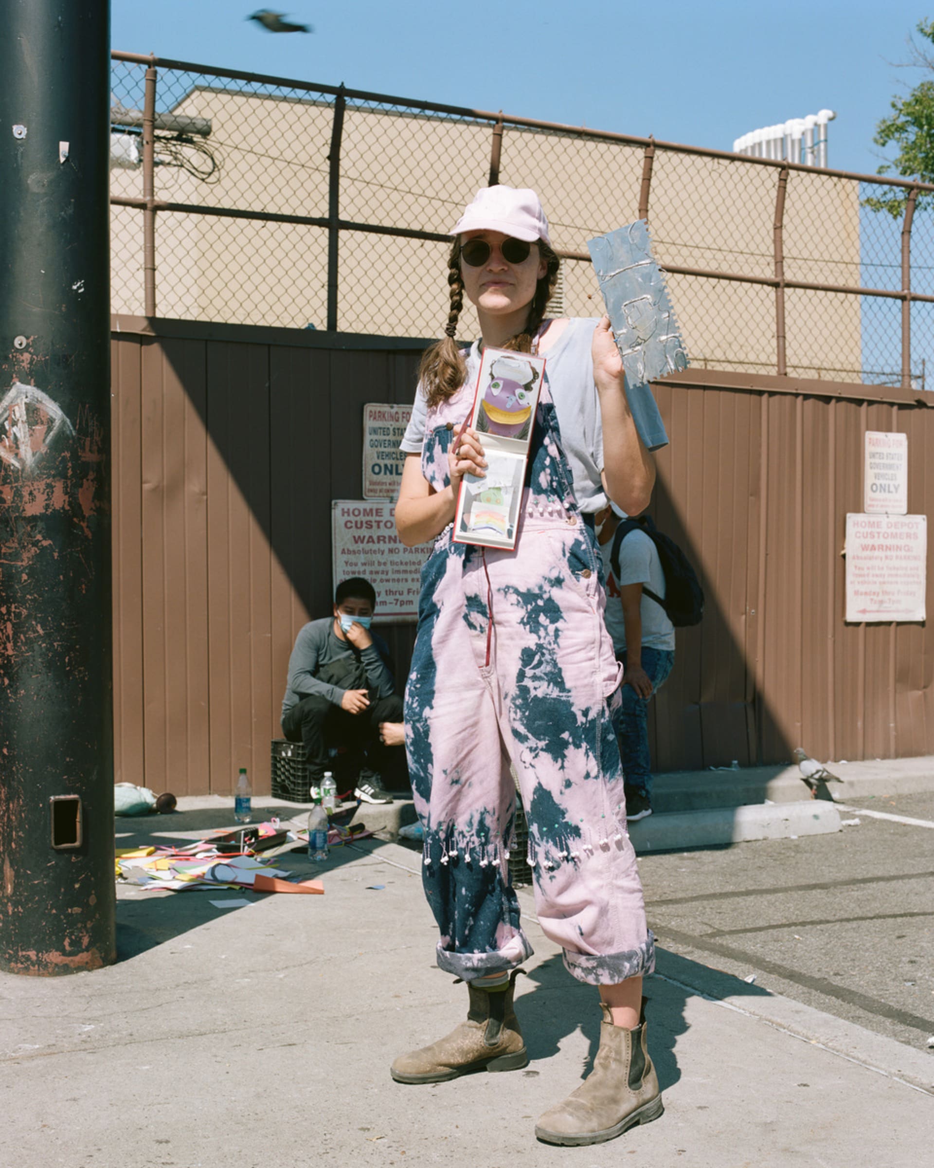 Simone is standing on a sunny day holding up a mask making device she made