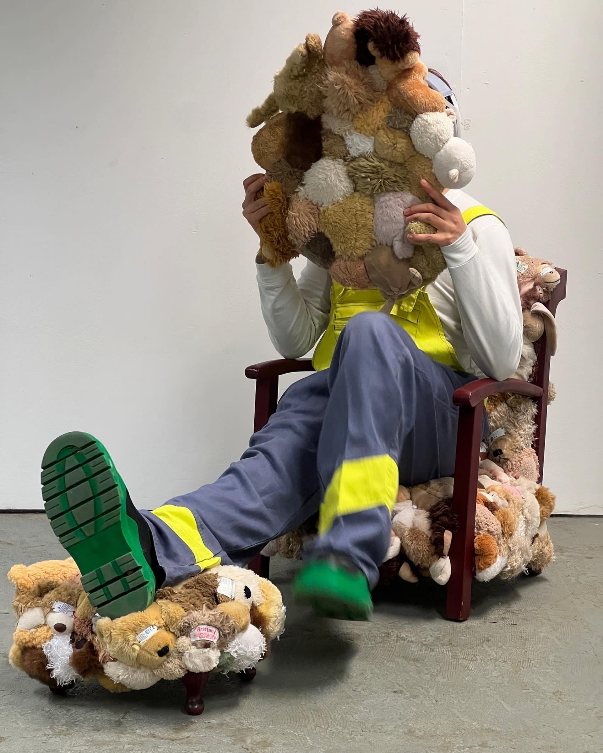 A person sitting on a chair, puts one of their feet on a stool, holding a rug. The chair stool and the rug are made of soft toy.