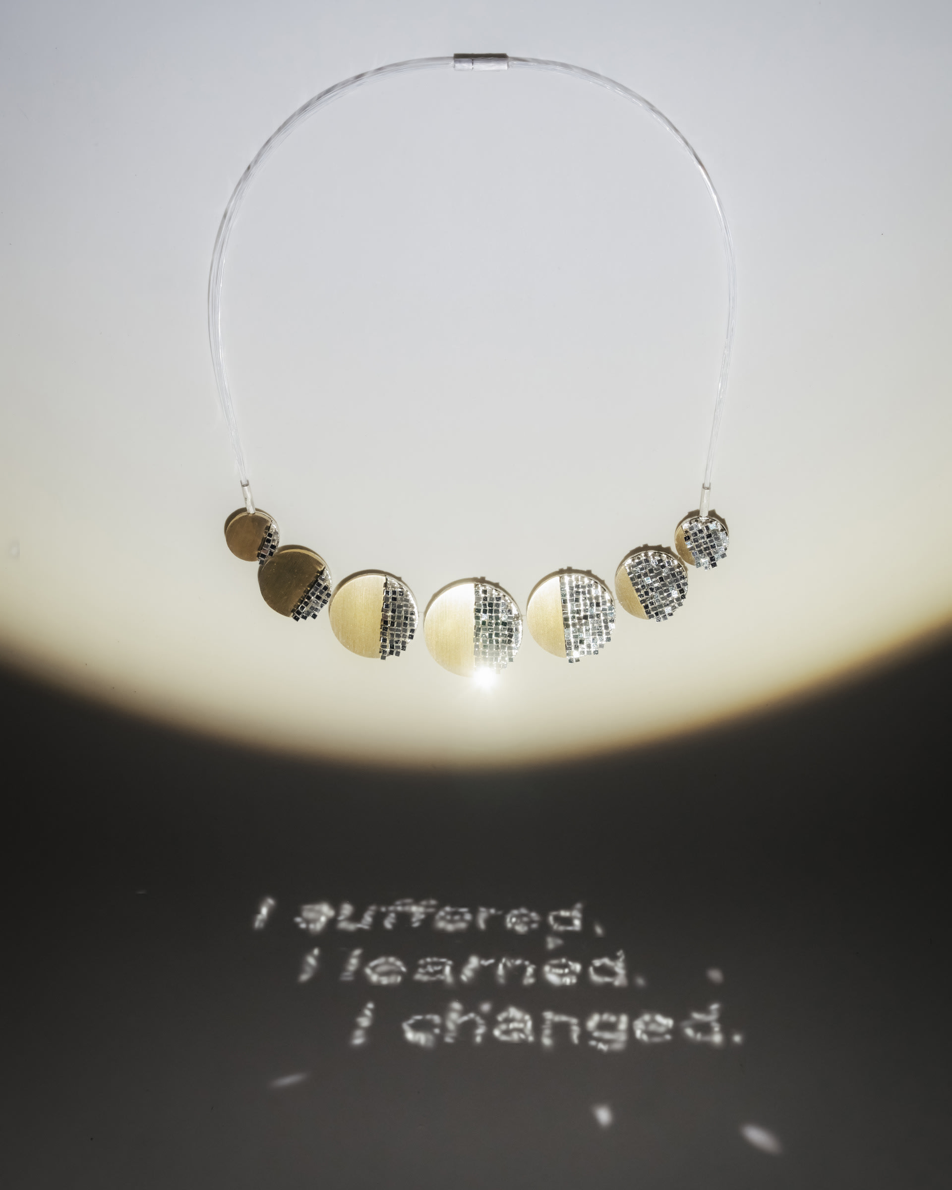 The light is reflected on the paper through the reflective surface of the jewellery to show a proverb