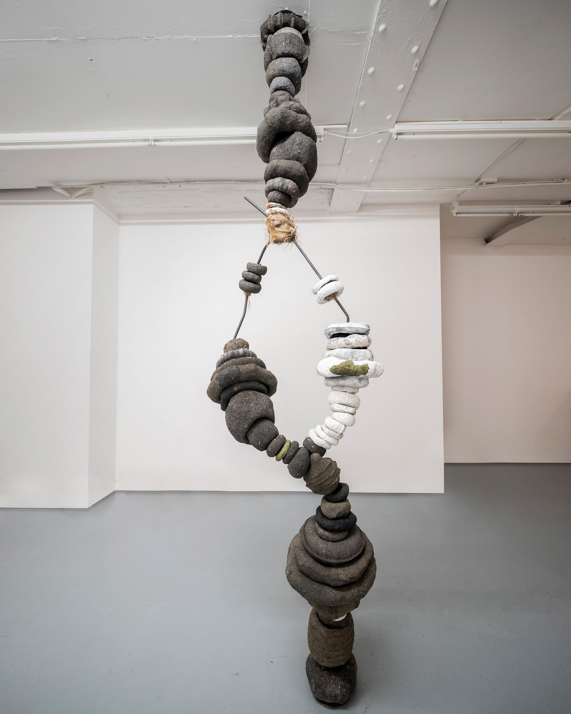 wide of sculpture, floor to ceiling looks like tree but branches join again, made of stacked rings and bare metal