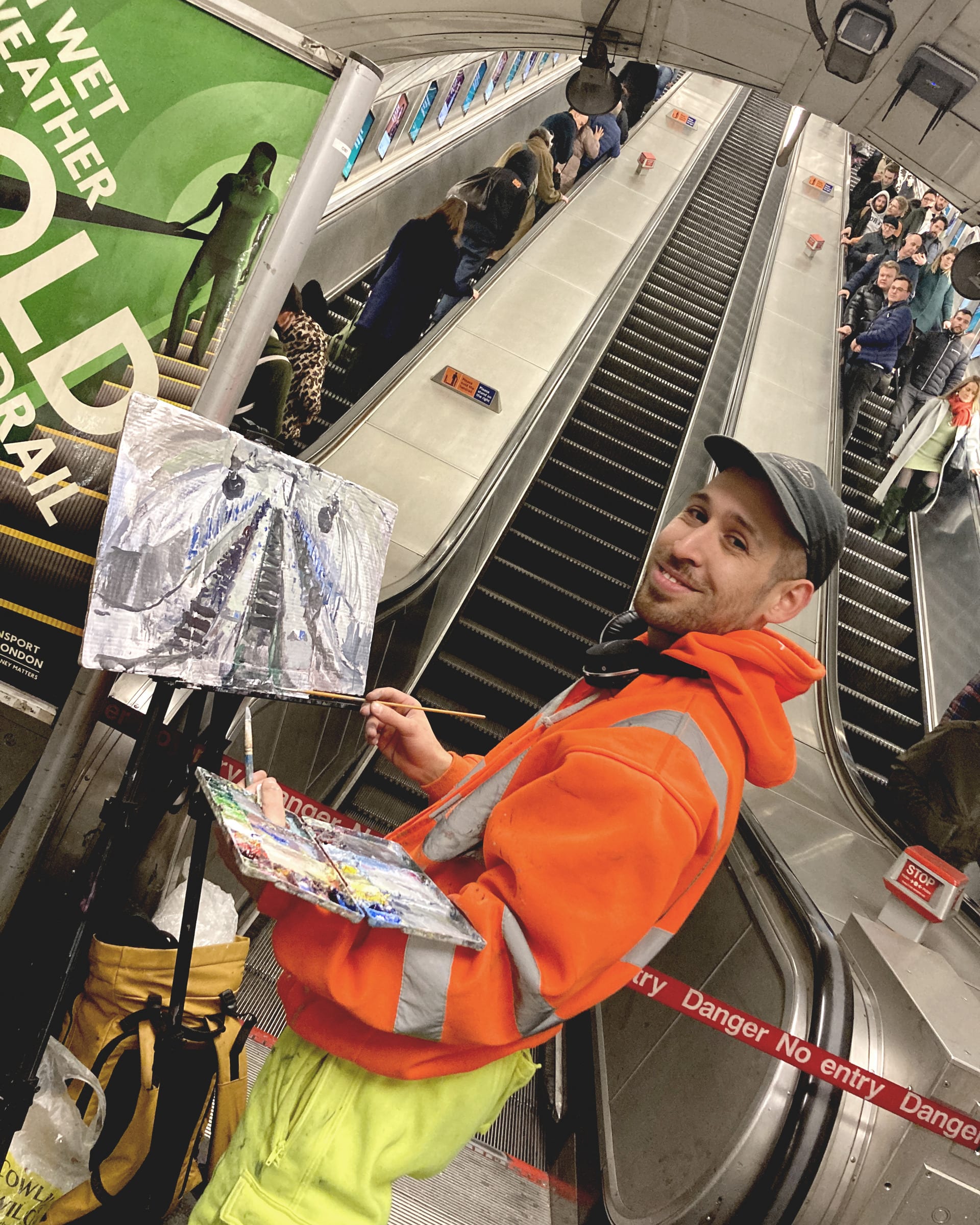 Artist painting from life with an easel standing in front of underground escalator