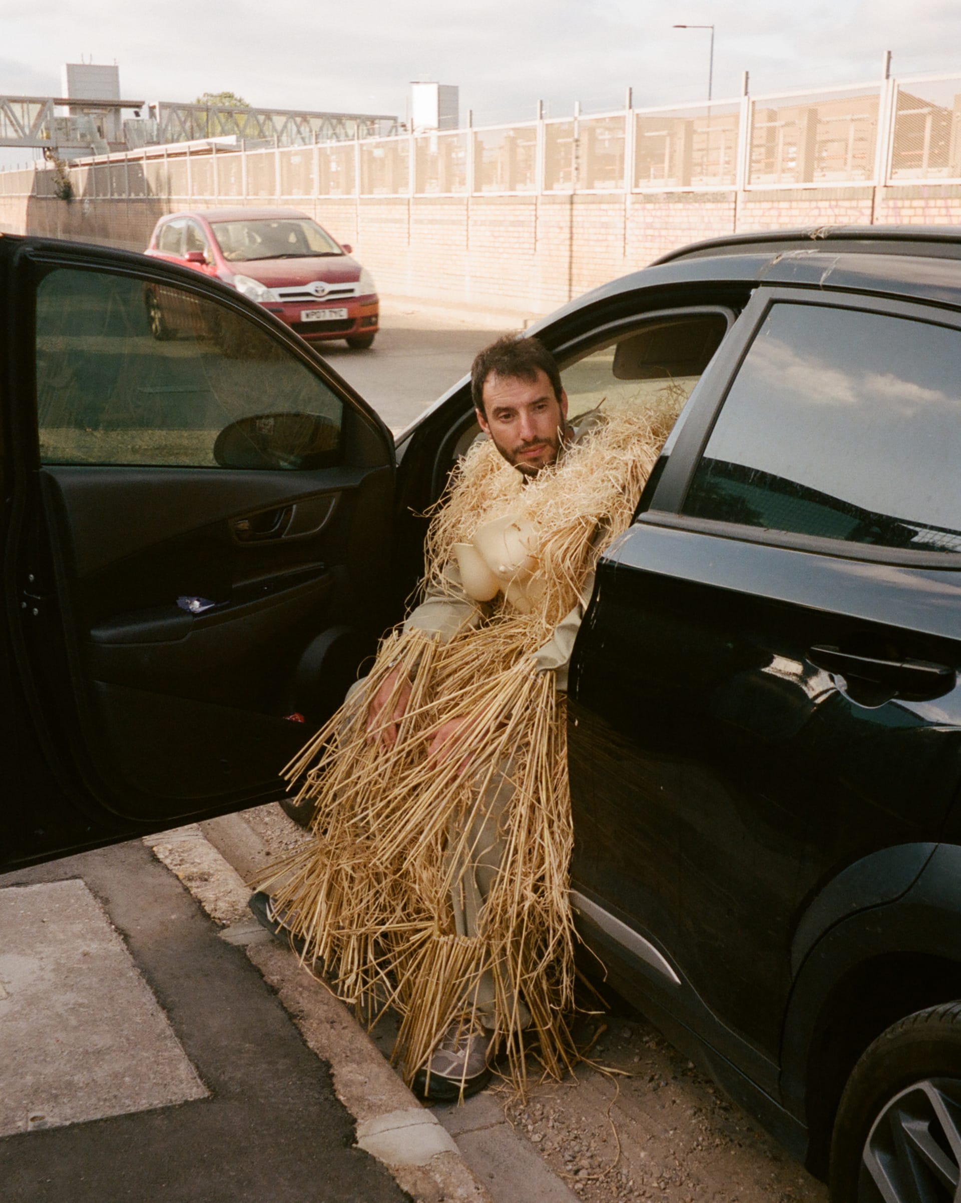 A lone figure of straw and masquerade standing in an urban landscape