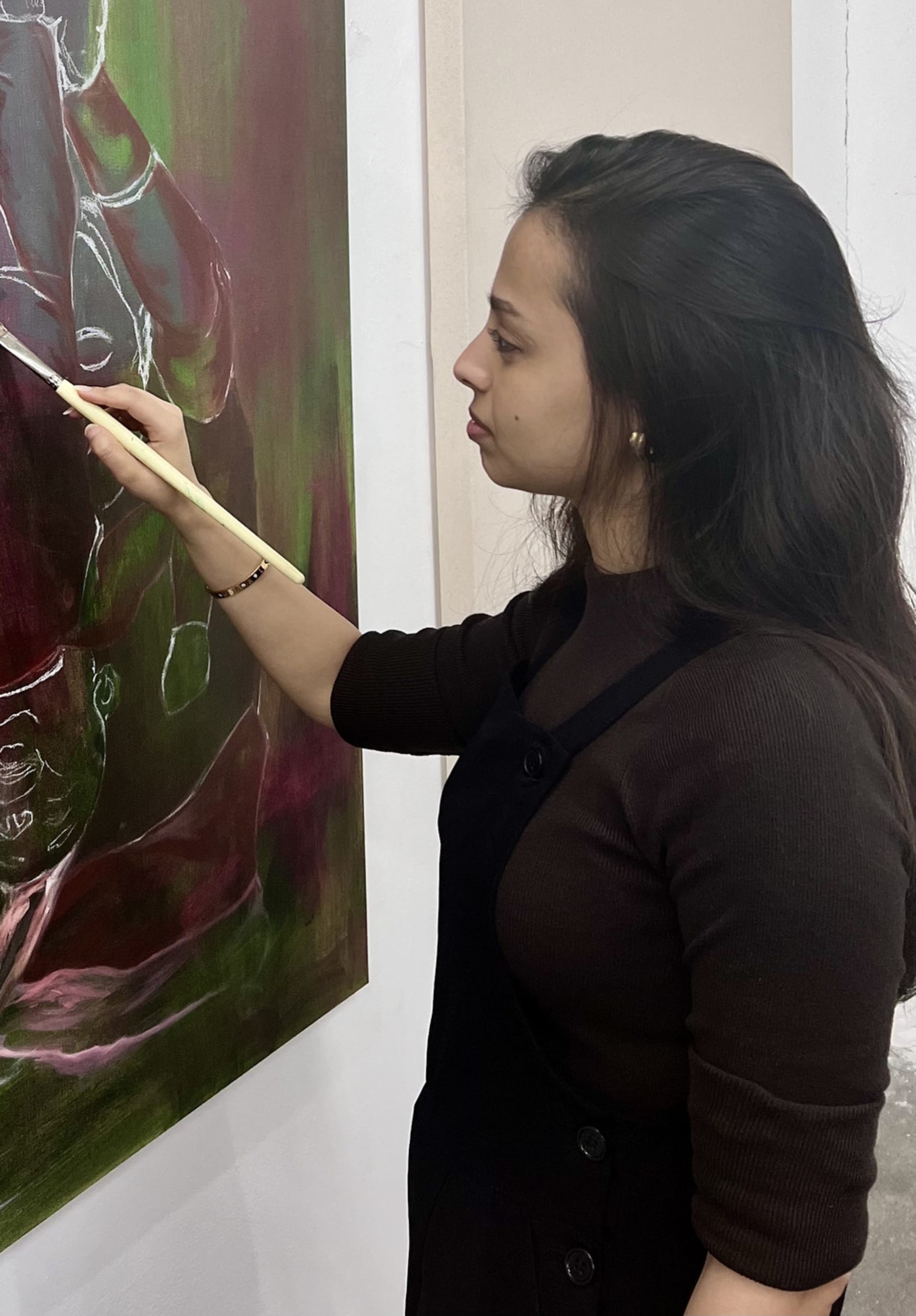 myself painting a green canvas hanging against a  a white studio wall 