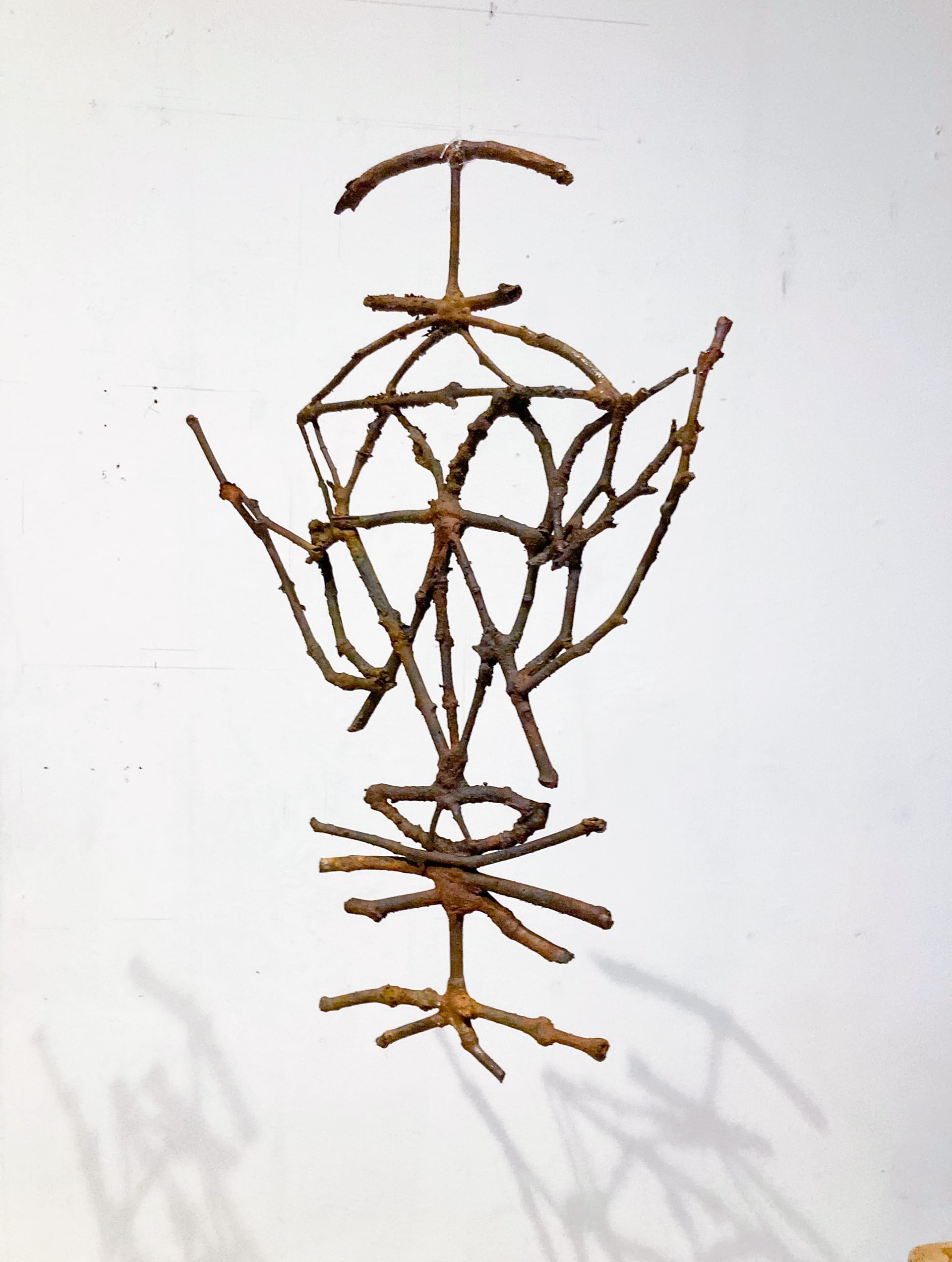 A hanging bronze twig sigil, colours are red brown.