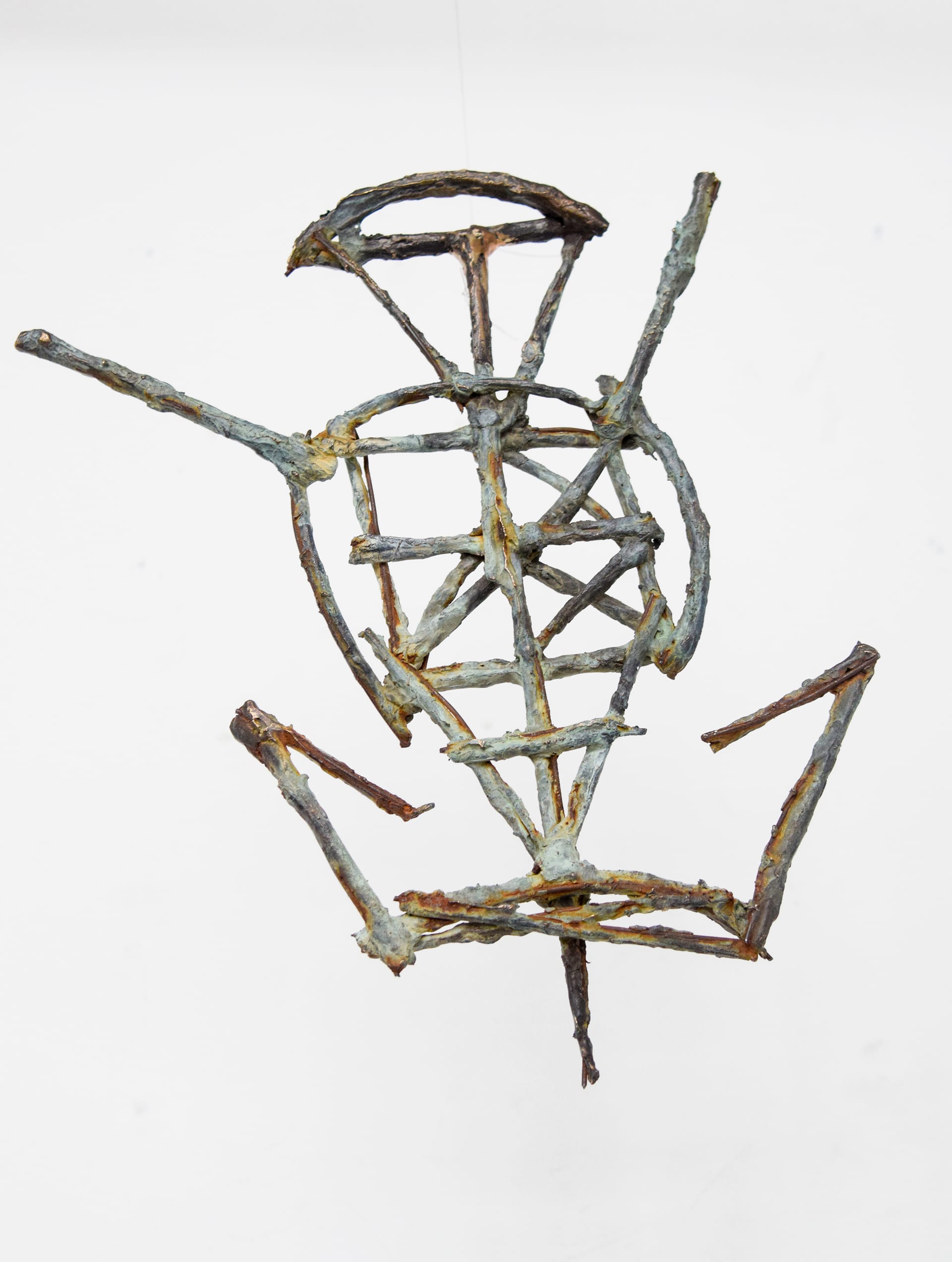 A hanging bronze twig sigil, colours are blue-green. 