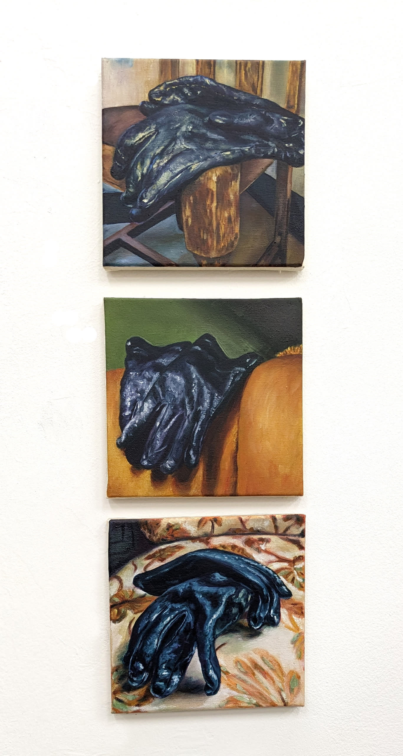 A series of three small oil paintings shows a pair of gloves resting on different chairs.