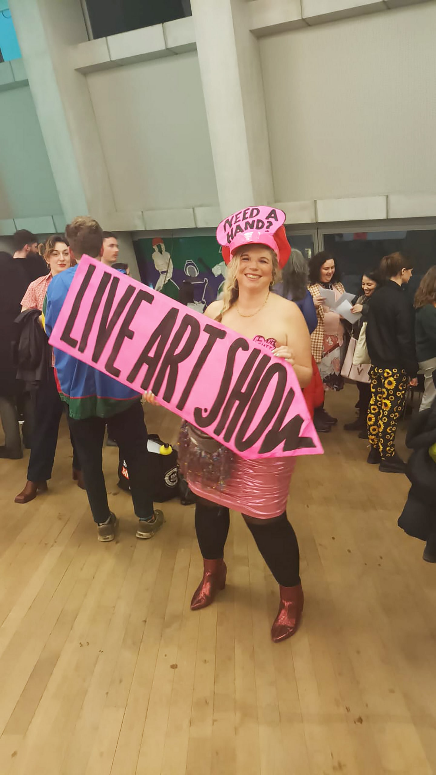 Mary Amelia London holds a large pink sign saying Live Art Show at Tate Late