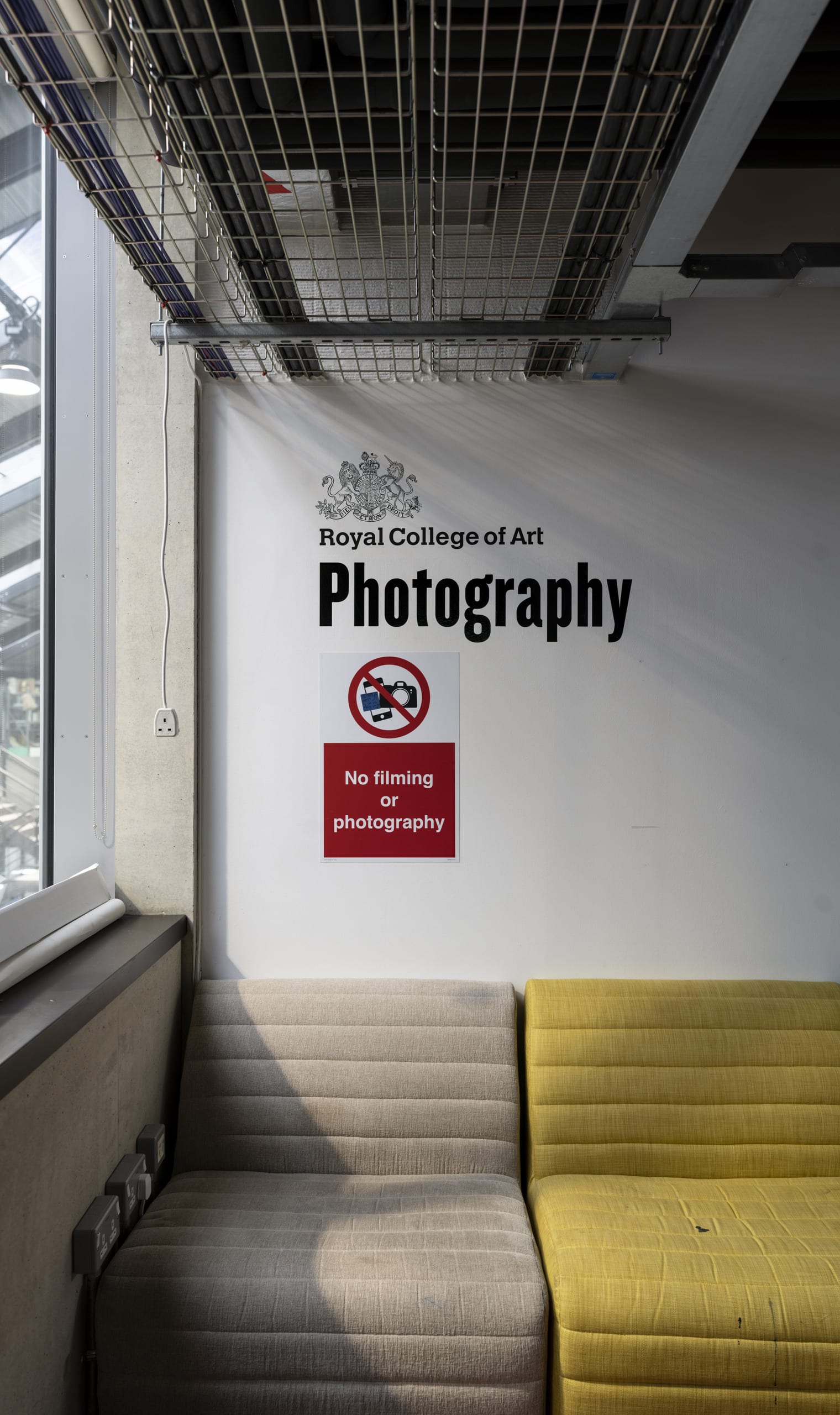 An image of the RCA photography sign with a "No Photography" sign underneath it. There is a window on the left and a sofa below 