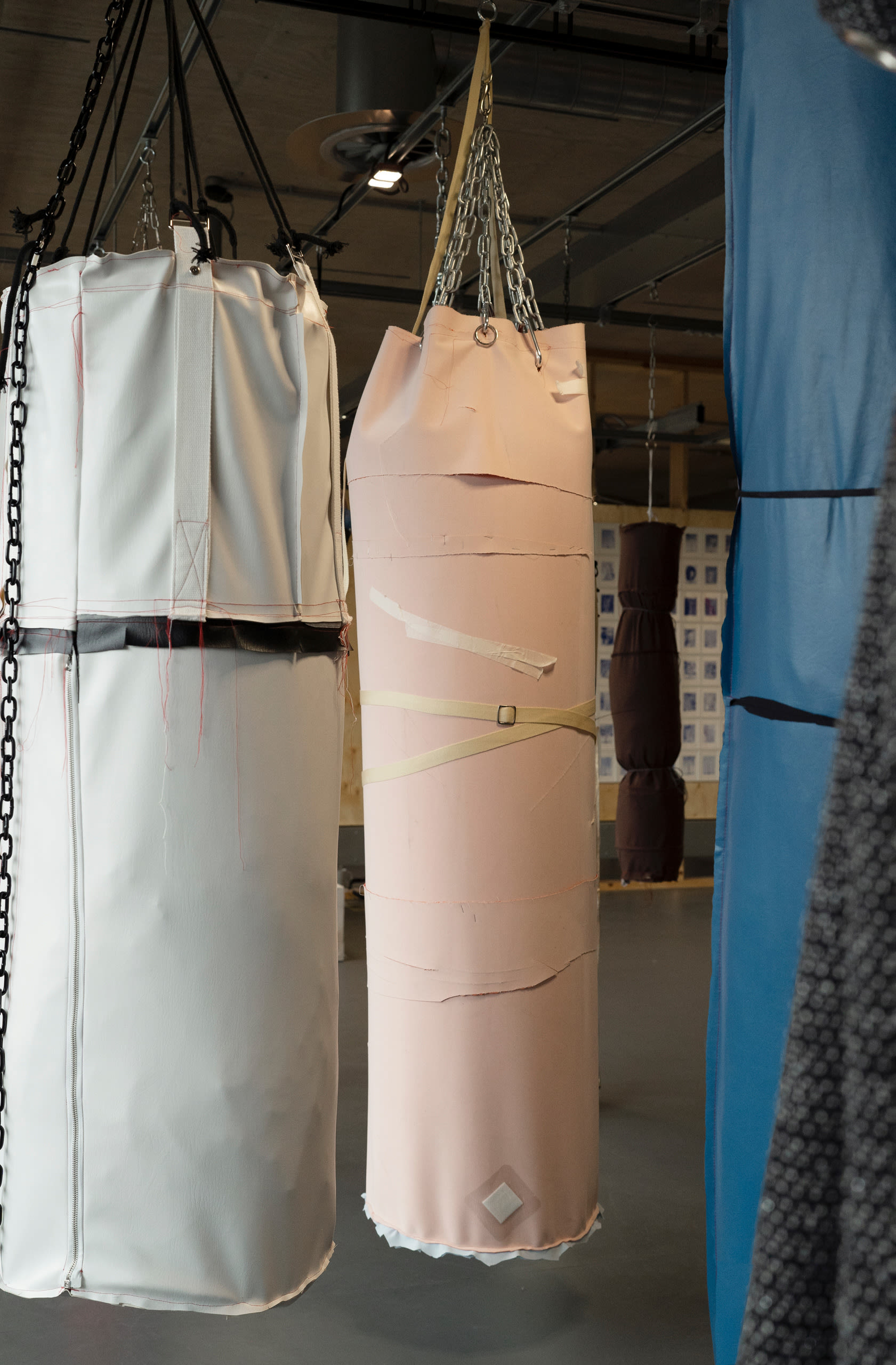 Two objects resembling punch bags hanging by thick chains (one black and white, the other pale orange)