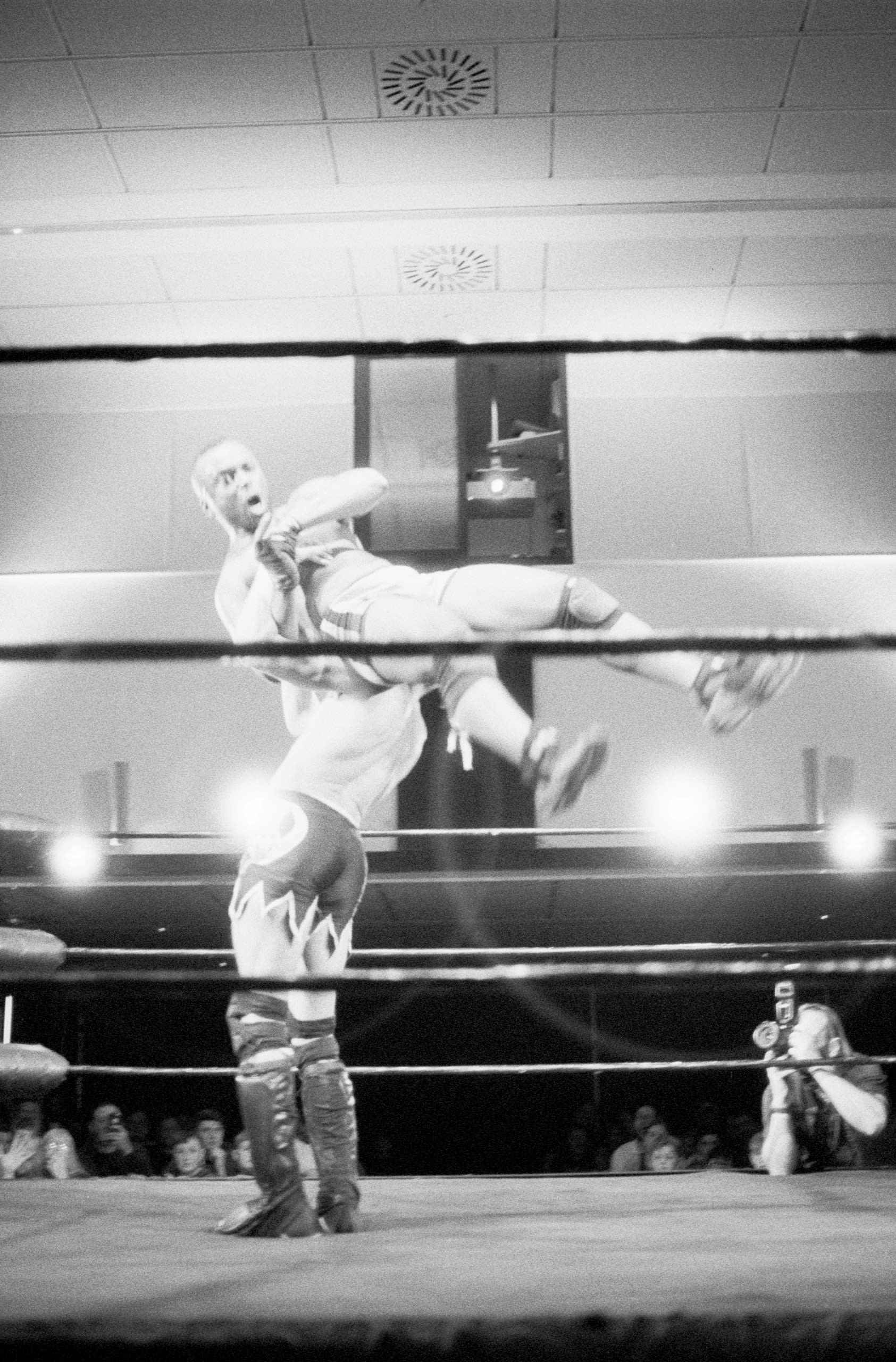 Two wrestlers engaging in a maneuver that throws one to the floor.