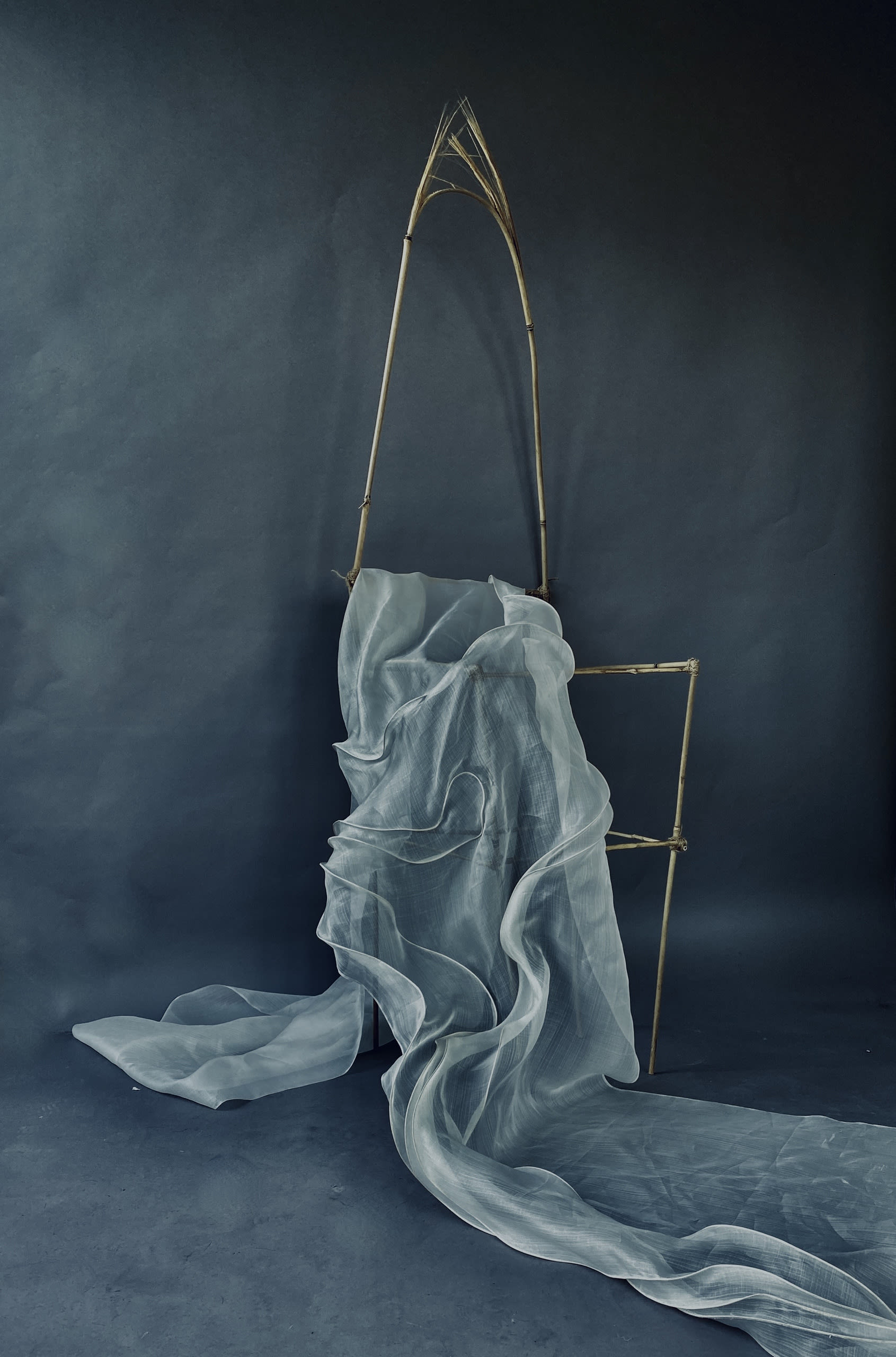 Bamboo chair sculpture with piña fabric running through the chair.