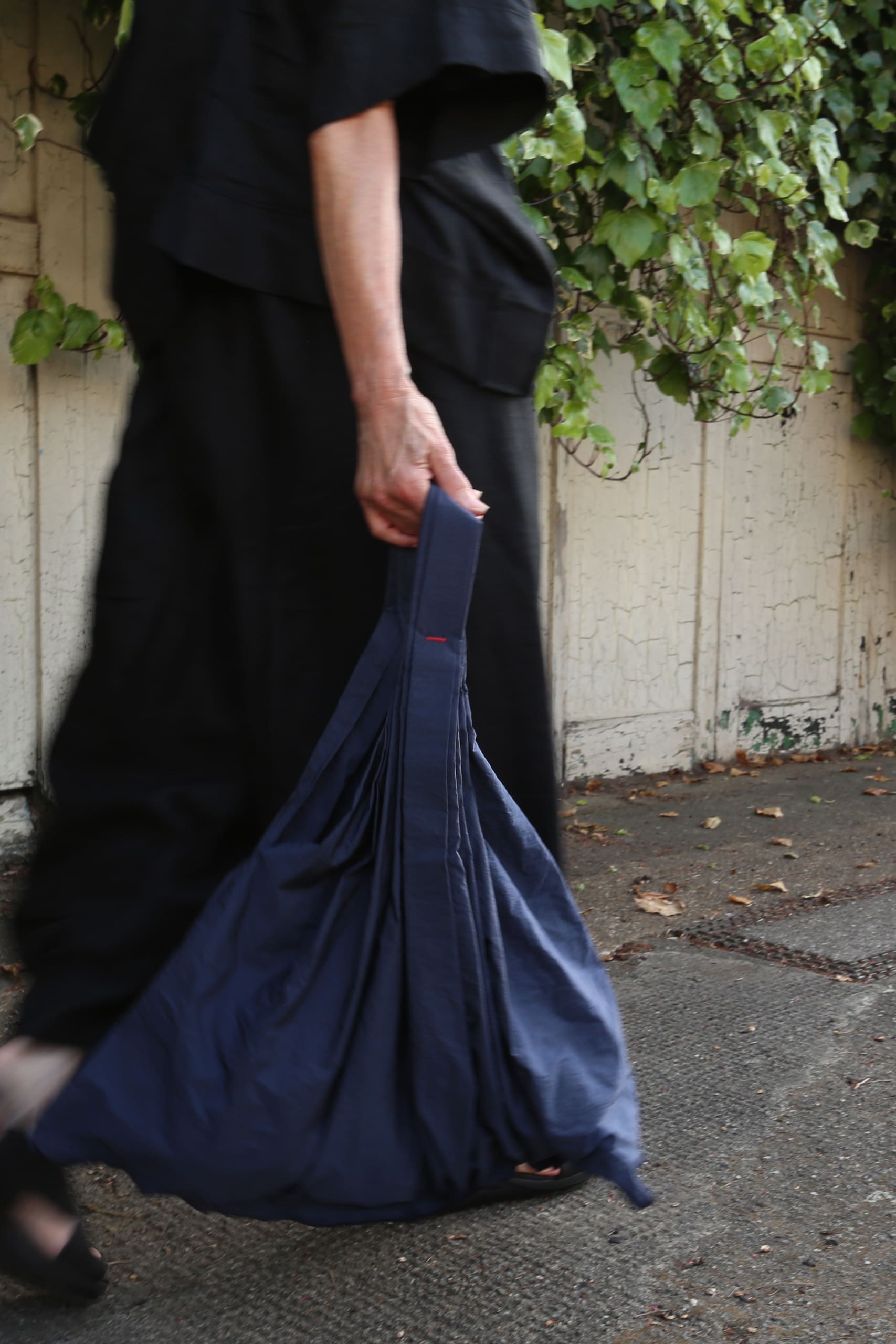 The blue steam pleated Ginko bag is held by someone walking past and is the only thing captured in focus