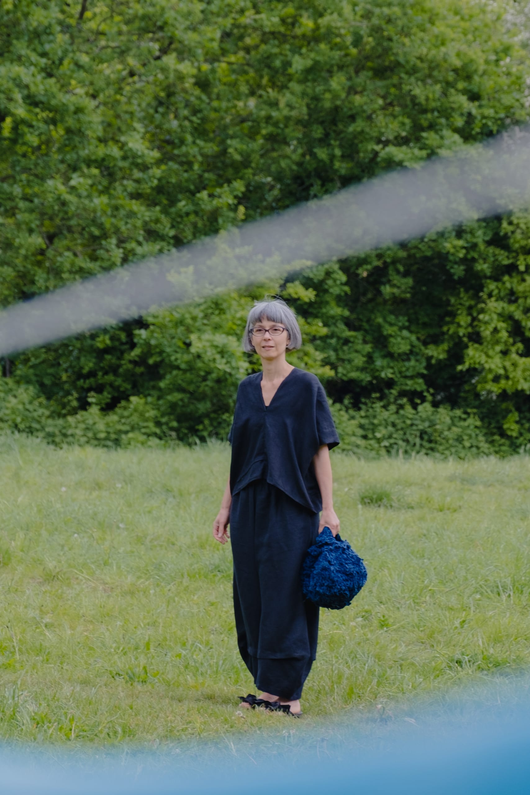 Between washing line and natural indigo scarf we see Jen wearing the 39.9 black linen top and trousers, holding the mini sakk