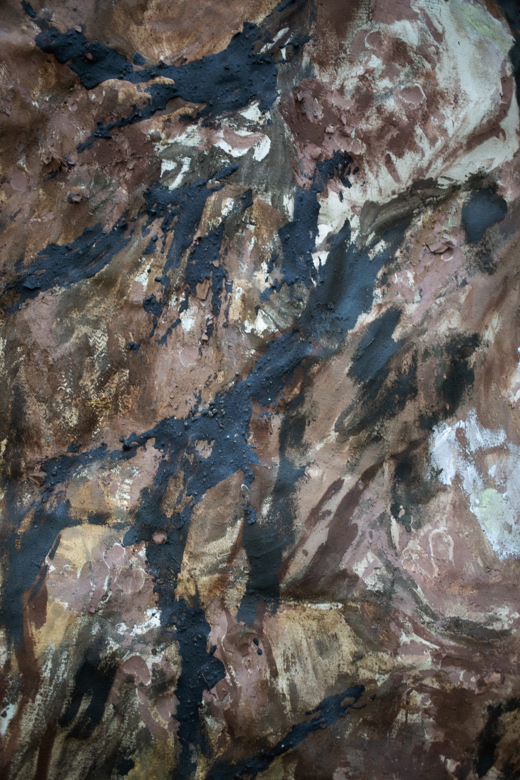 close up of warm brown painting; dark streaks of soil web through the canvas