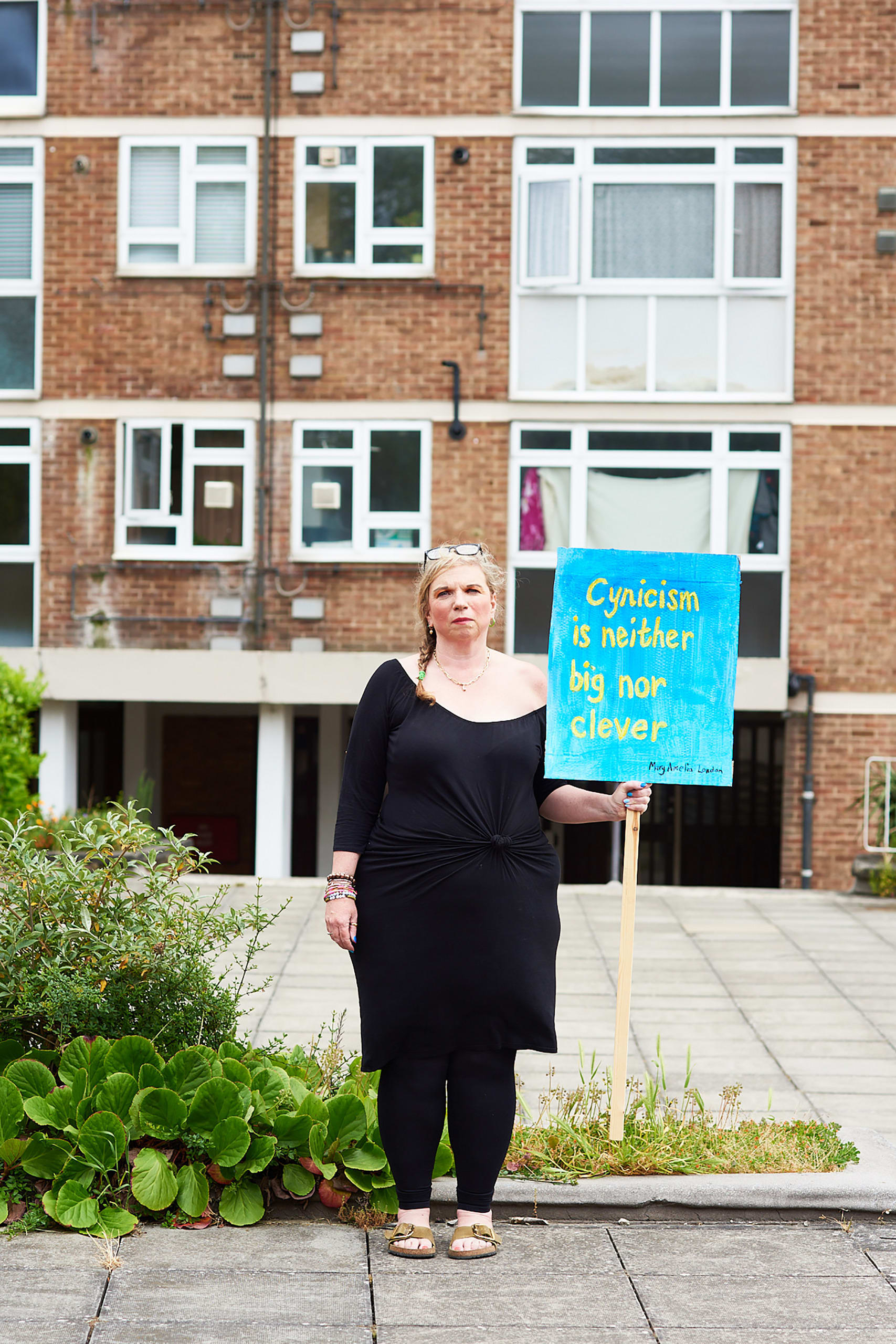 Mary Amelia London stands holding a sign saying: 'Cynicism is neither big nor clever?'