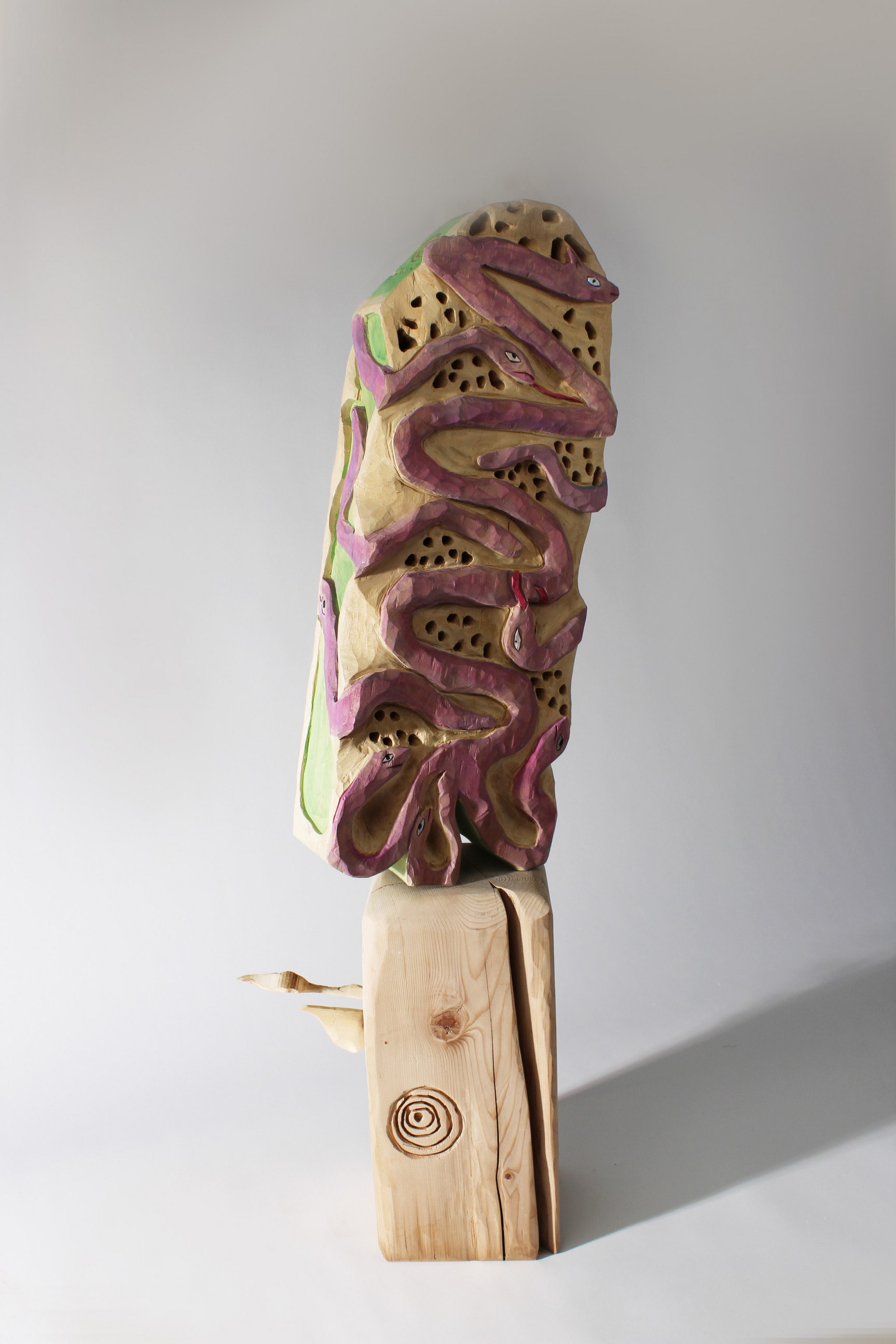 carved purple snake like, some eared worms wrap around a long piece of carved wood