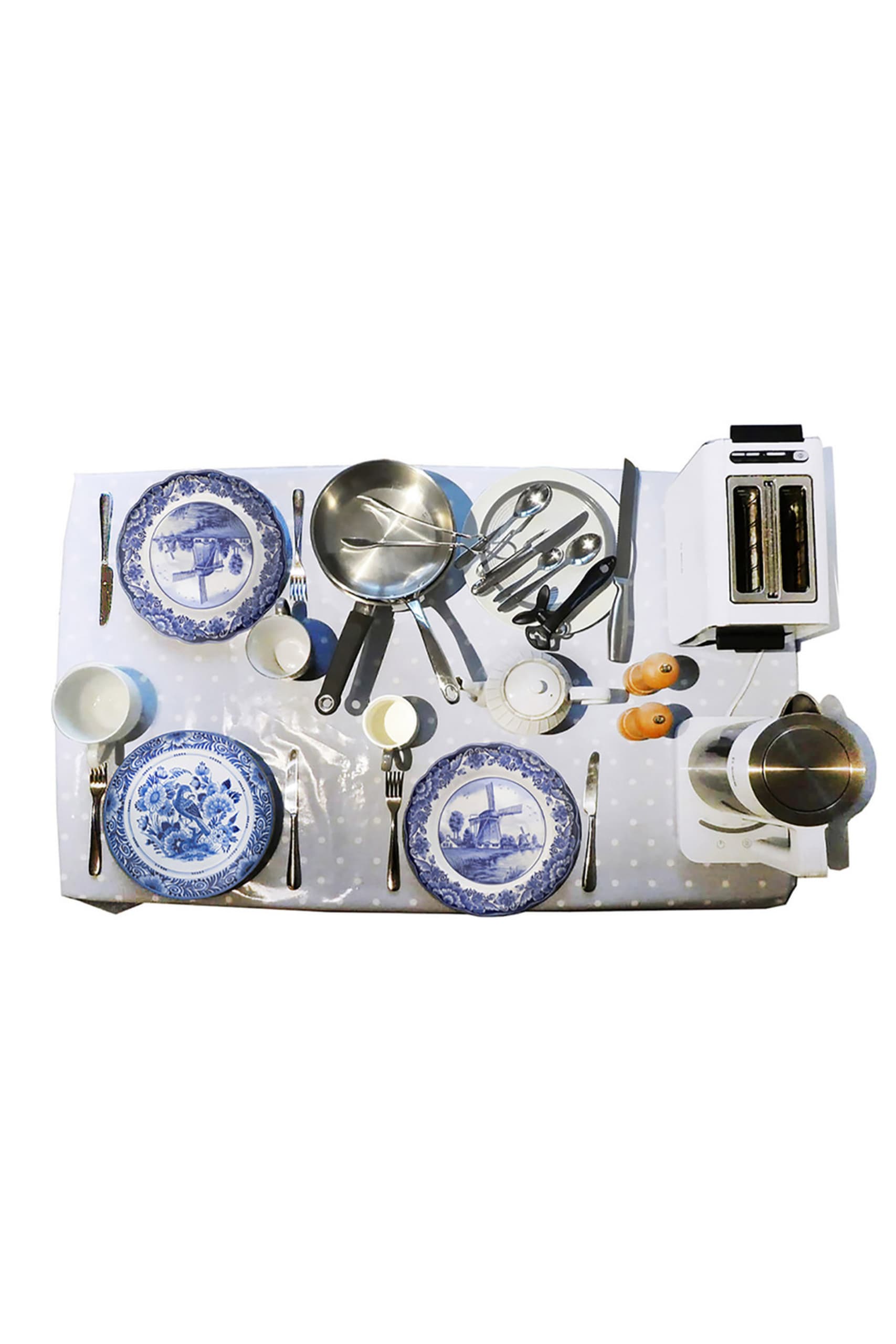 Plan View of a dining table with blue and white polka dot table cloth. Table is laid with three Delft plates and appliances.