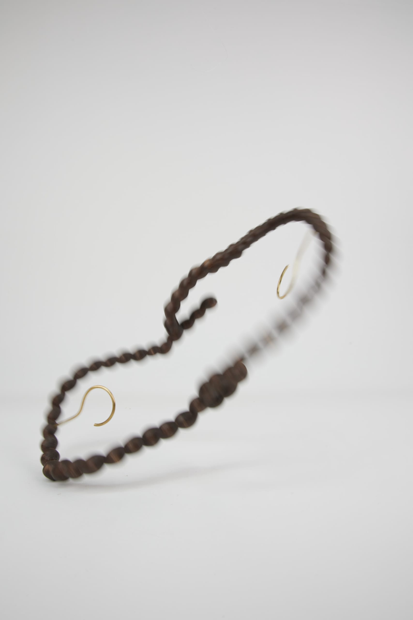 a string of hand-carved wooden pearls with a brass hook on top