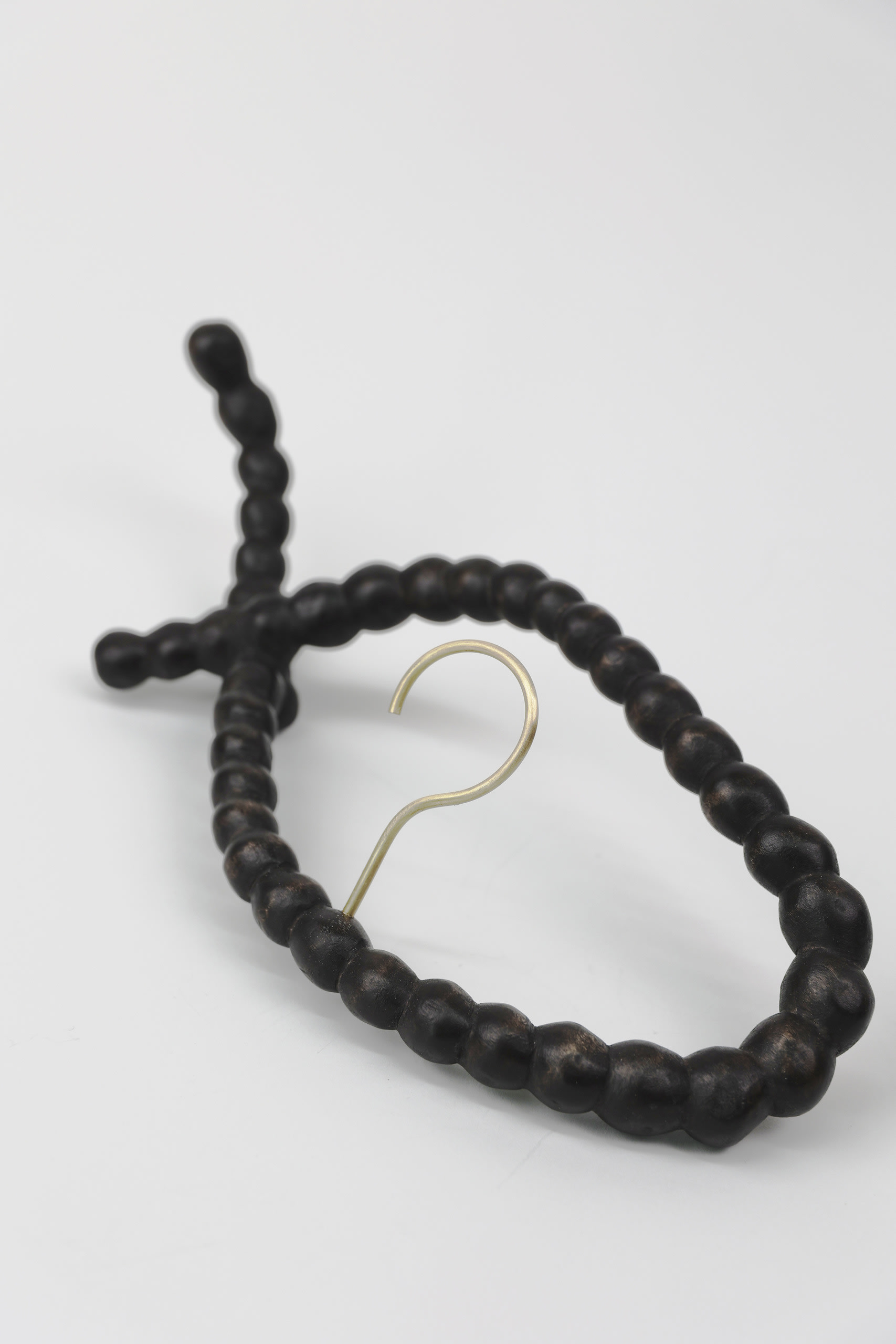 a string of hand-carved wooden pearls with a brass hook set in the middle