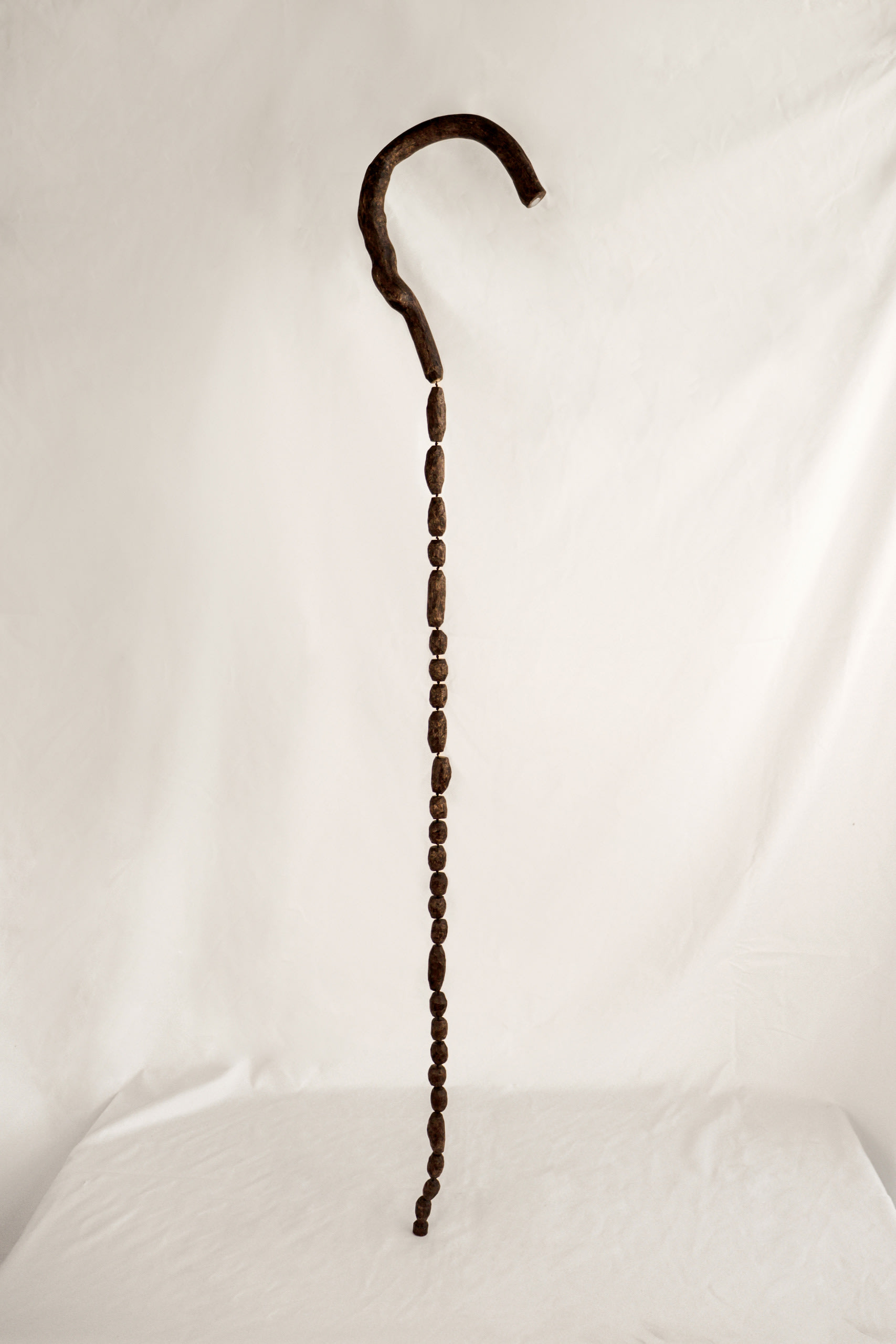 a walking stick being cut and carved into little wooden beads and stringed back together.