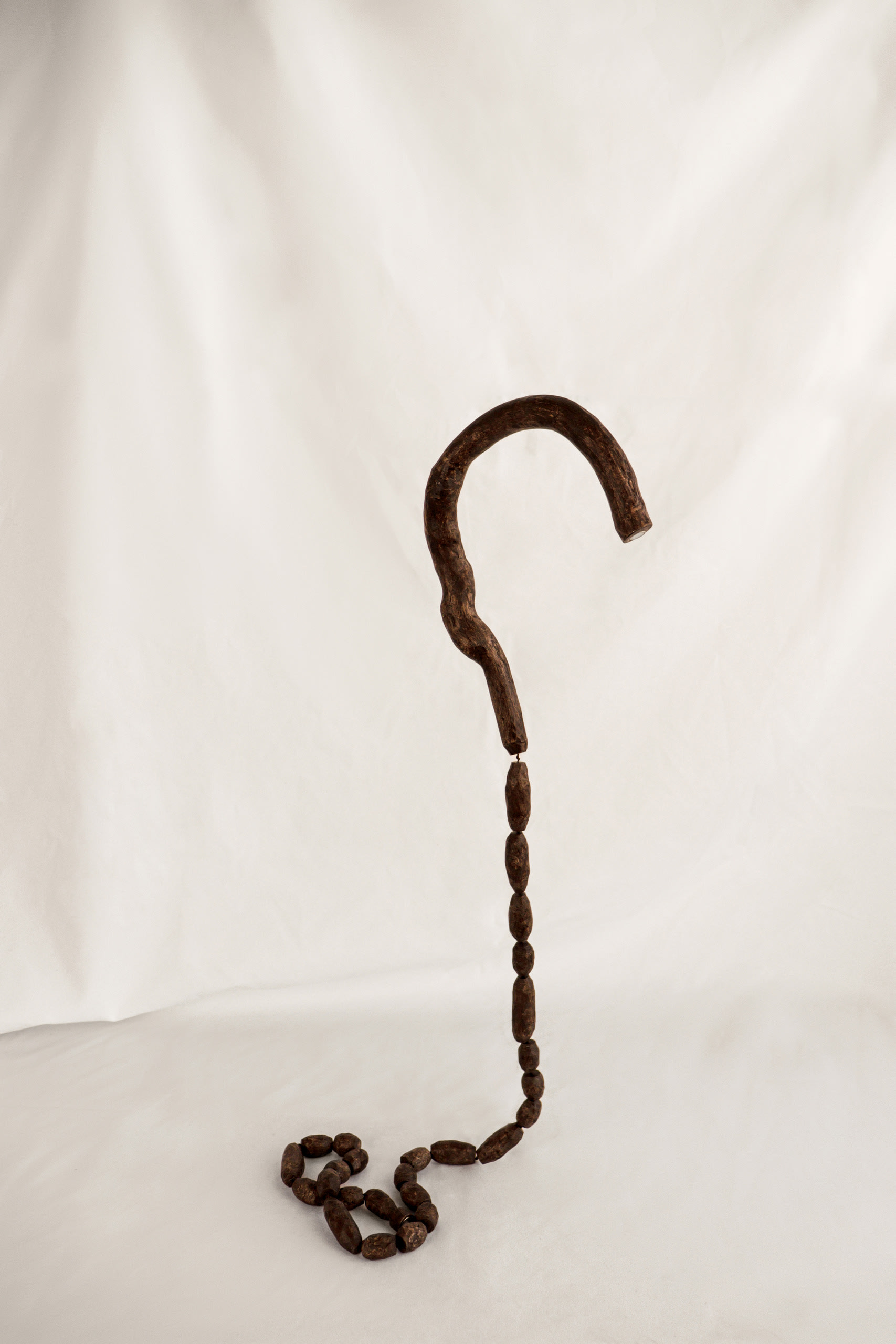 a walking stick being cut and carved into little wooden beads and stringed back together.