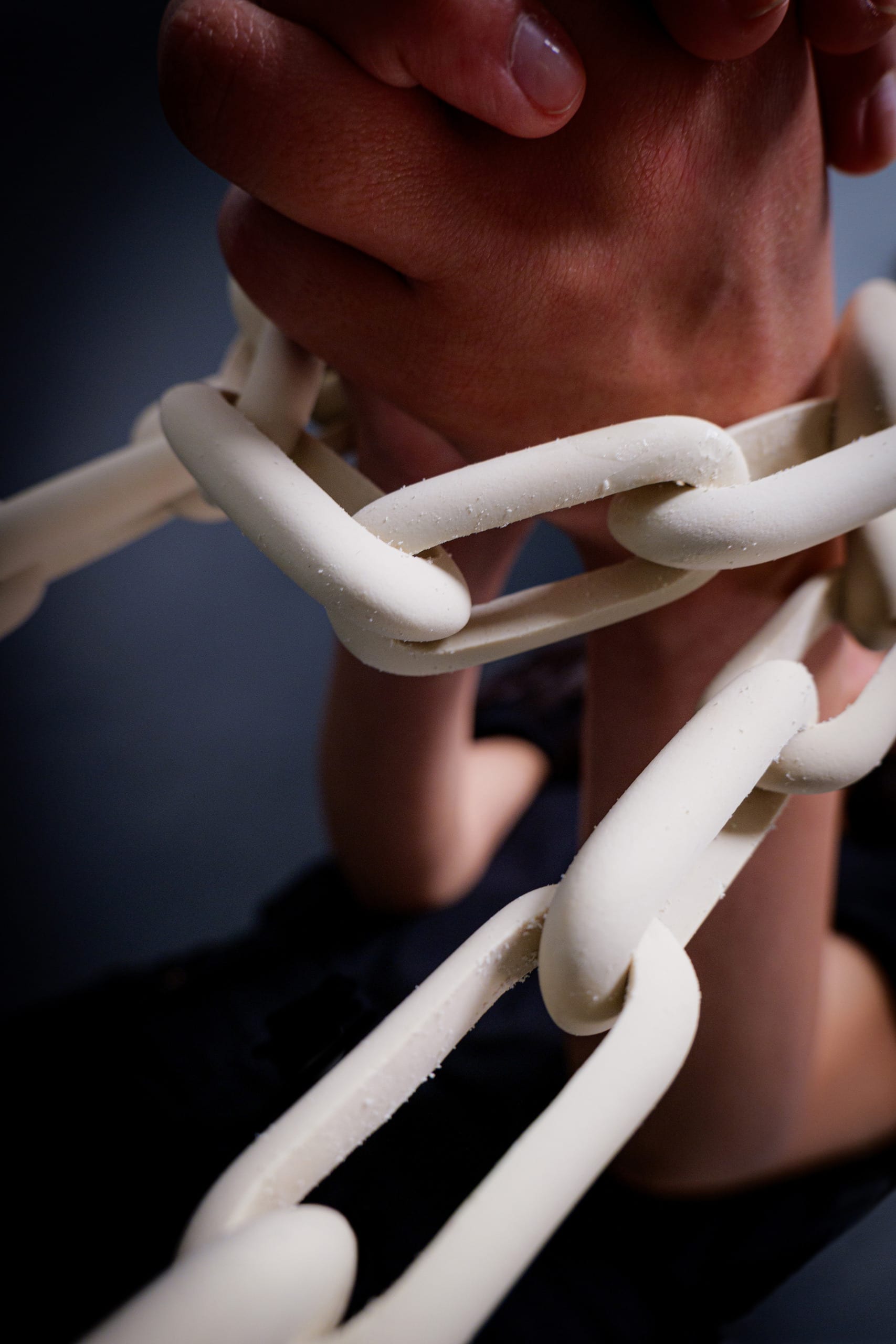 chain made from oval eraser twisted around hands/close-up image