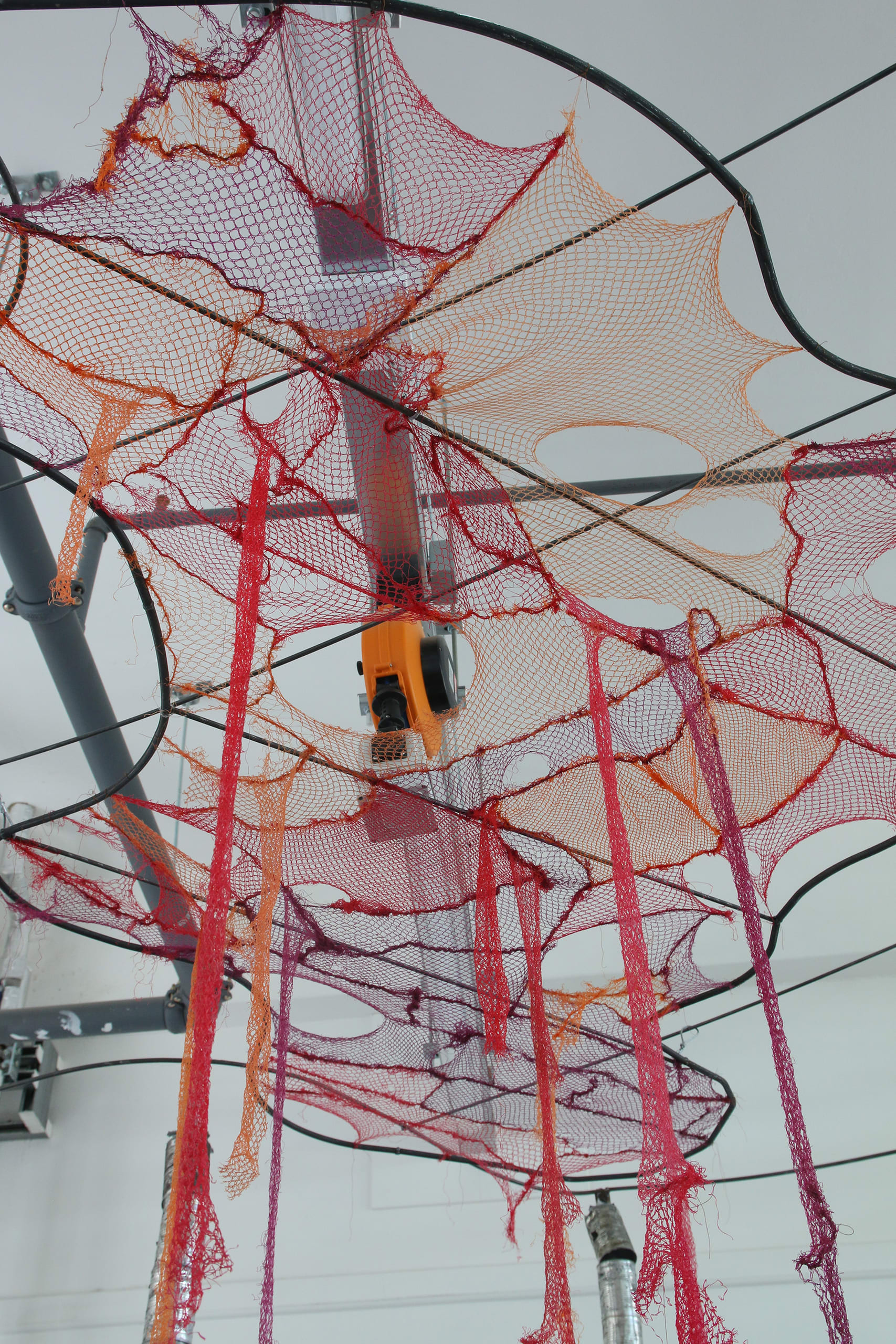 Another close up shows the cloud of red, orange & purple mesh stitched together and supported by a curved metal frame.