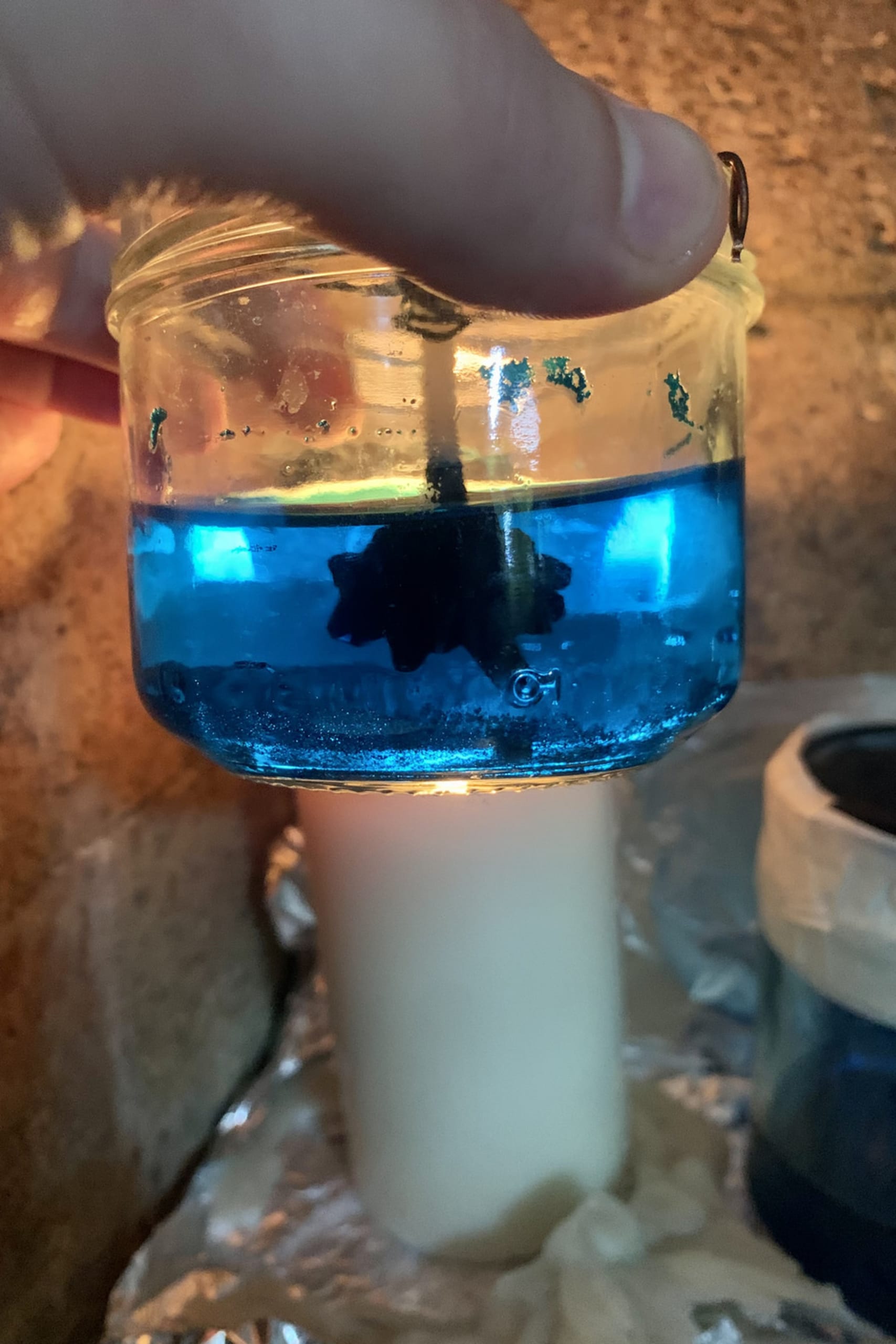 Copper acetate solution in glass jar. 