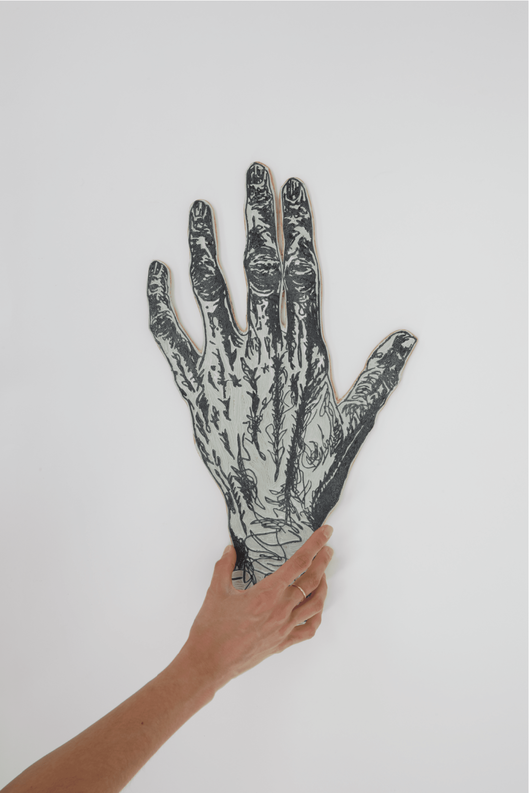 A hand holding a linoleum carving of a hand