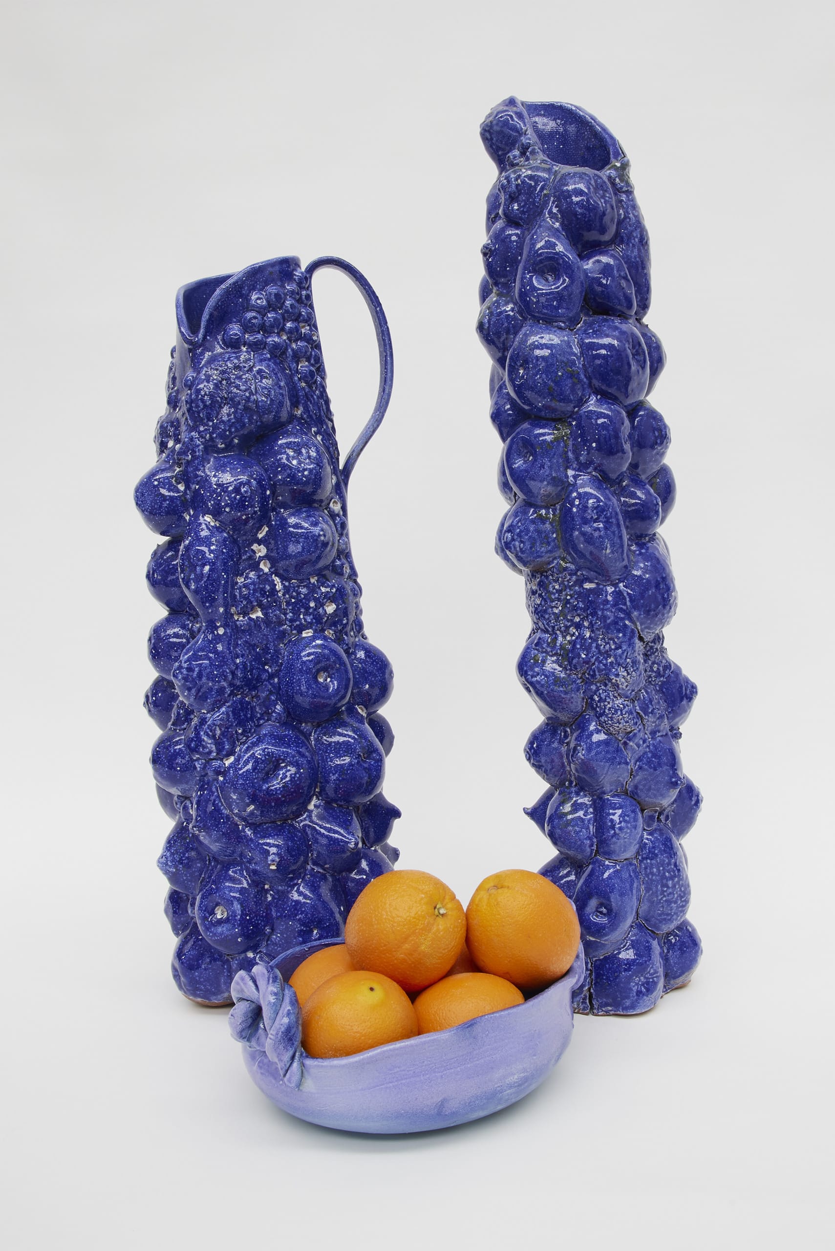 Two large ceramic jugs in blue, decorated with fruit forms.