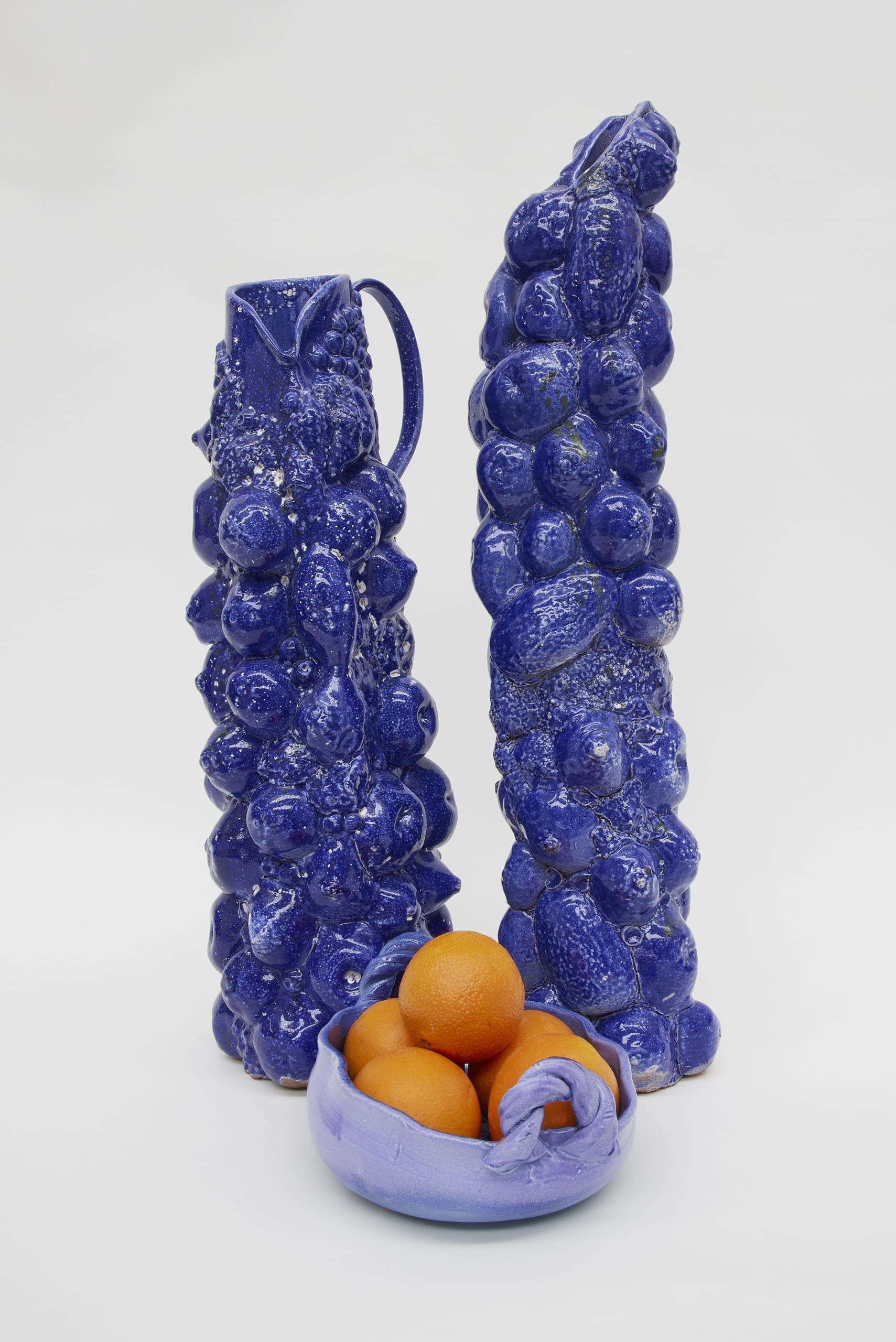 Two large ceramic jugs in blue, decorated with fruit forms.