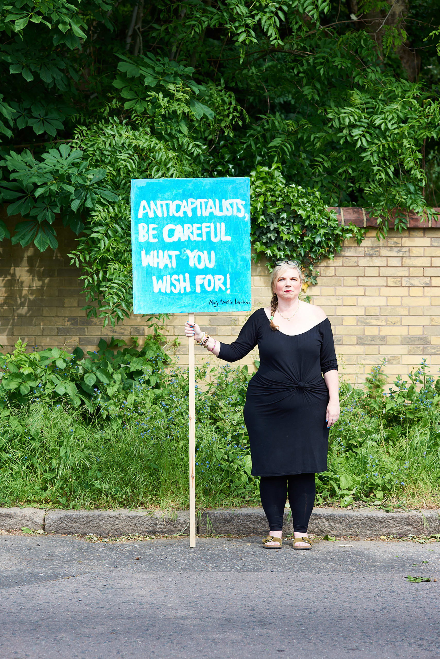 Mary Amelia London stands holding a sign saying: 'Anticapitalists be careful what you wish for'