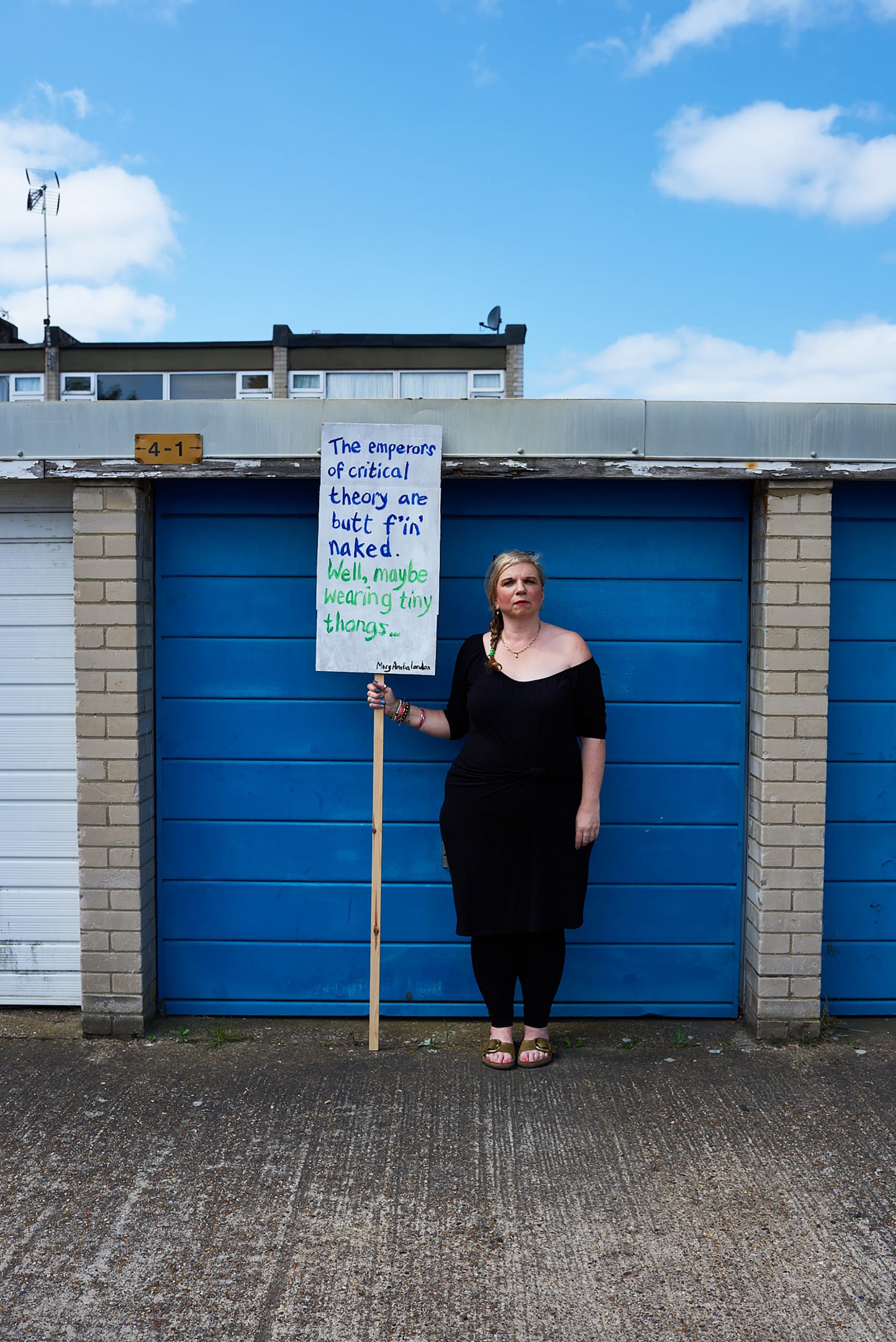 Mary Amelia London stands holding a sign saying: 'The emperors of critical theory are butt f'in' naked.'