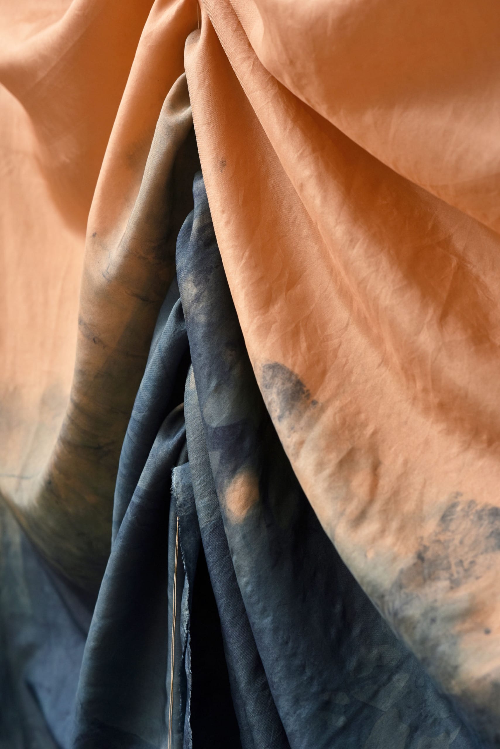 detail of draped fabric peachy colour with ombre of indig