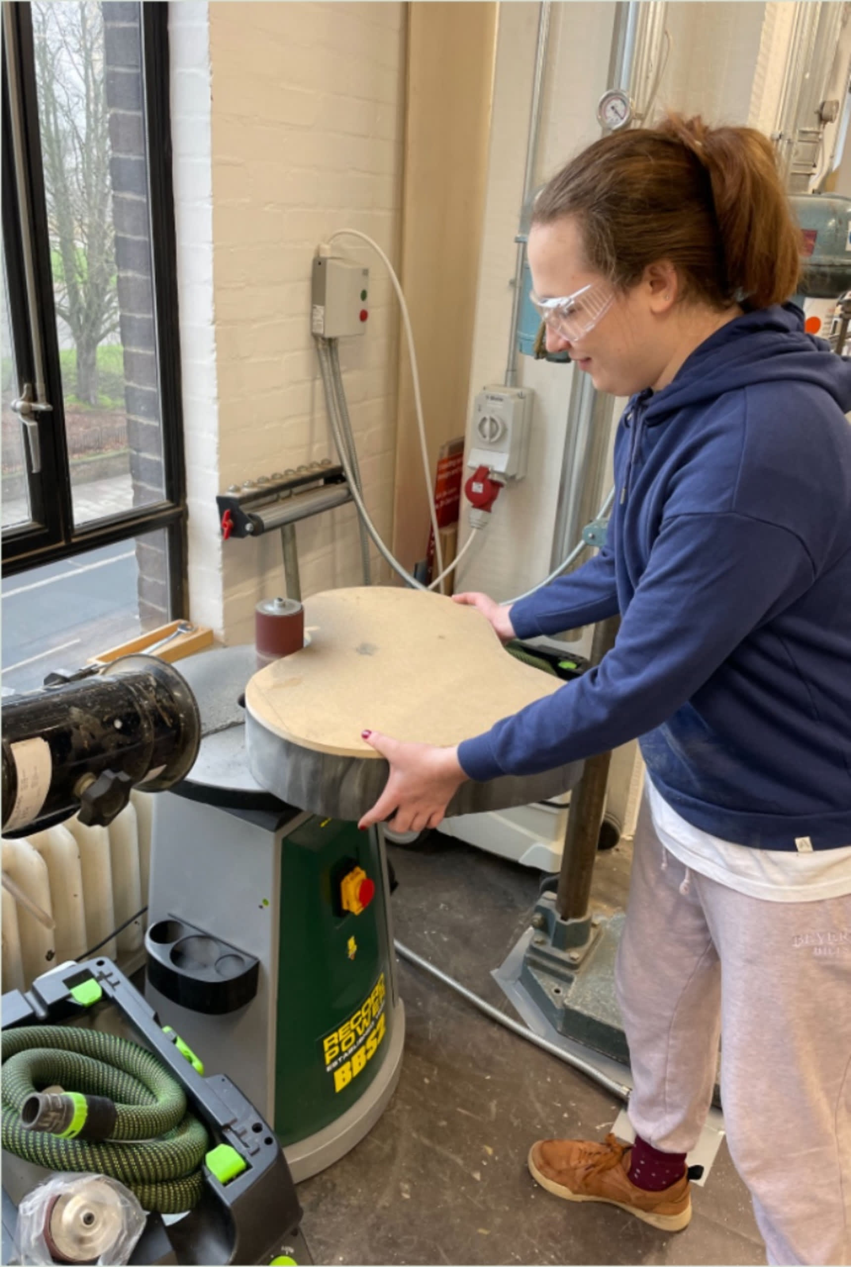Cas is using a sander to shape the curves of the base.