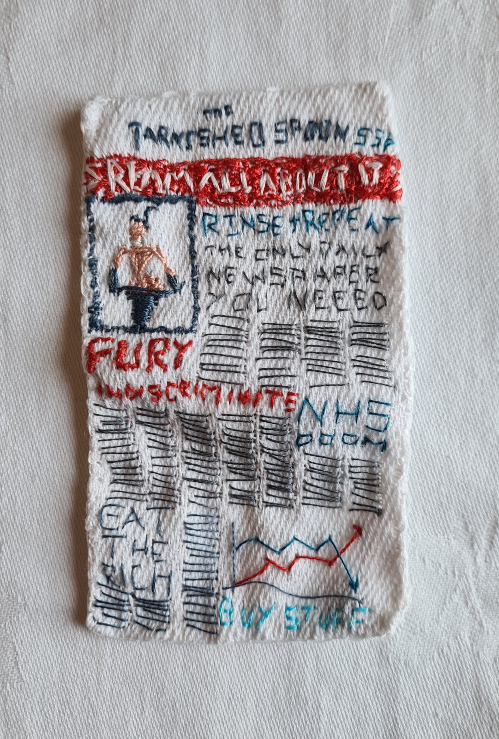 miniature newspaper embroidered  text and images on scrap of glass cloth 