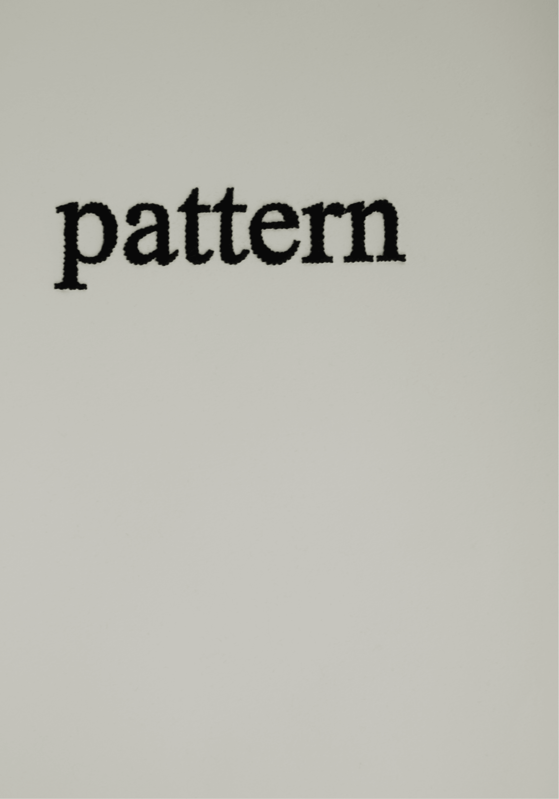 the word "pattern" embroidered with black thread on paper