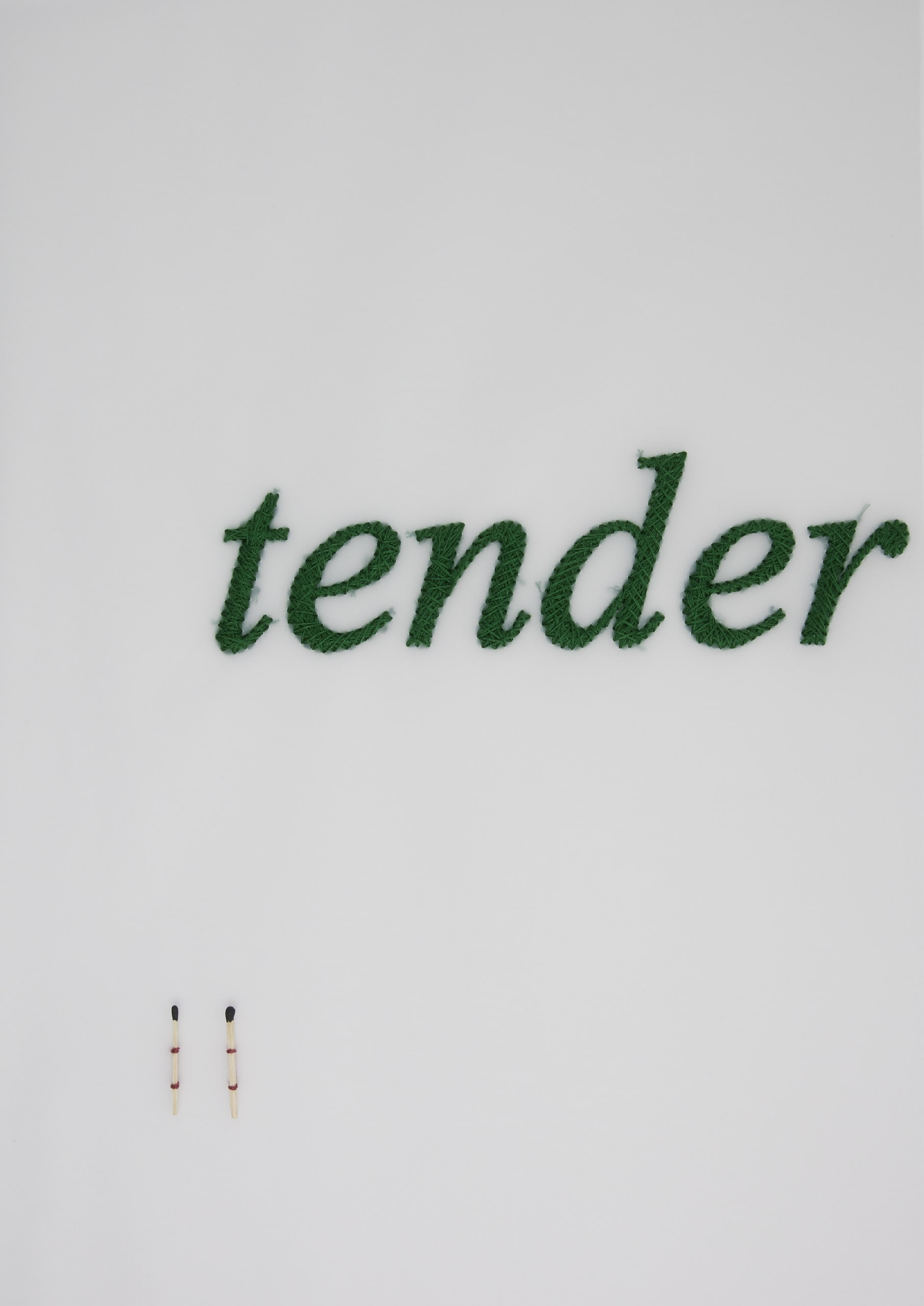 the word "tender" embroidered on tracing paper with a pair of matches