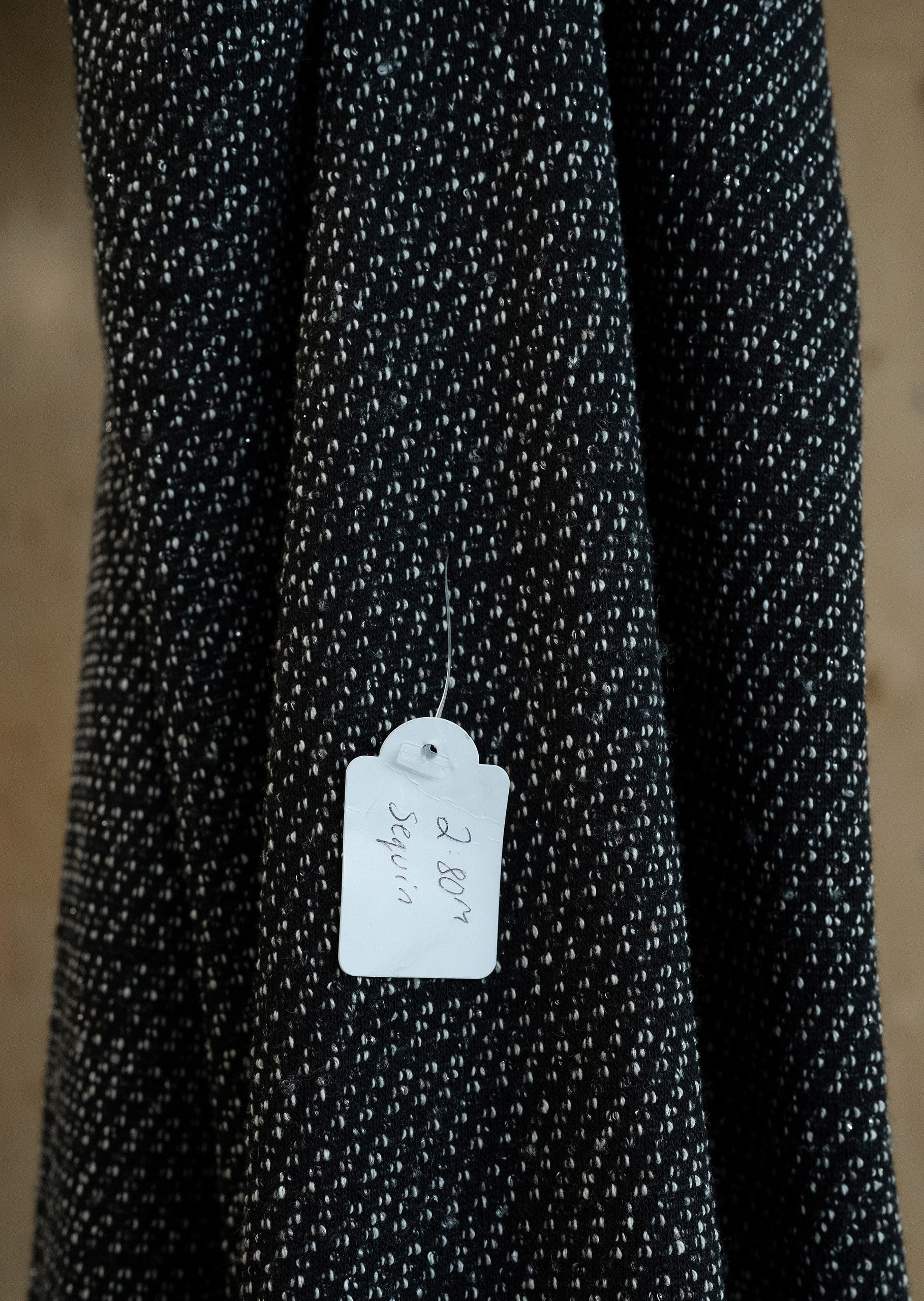 Close-up detail of black and white stretch fabric with incongruous shop tag that reads '2.80m Sequin'