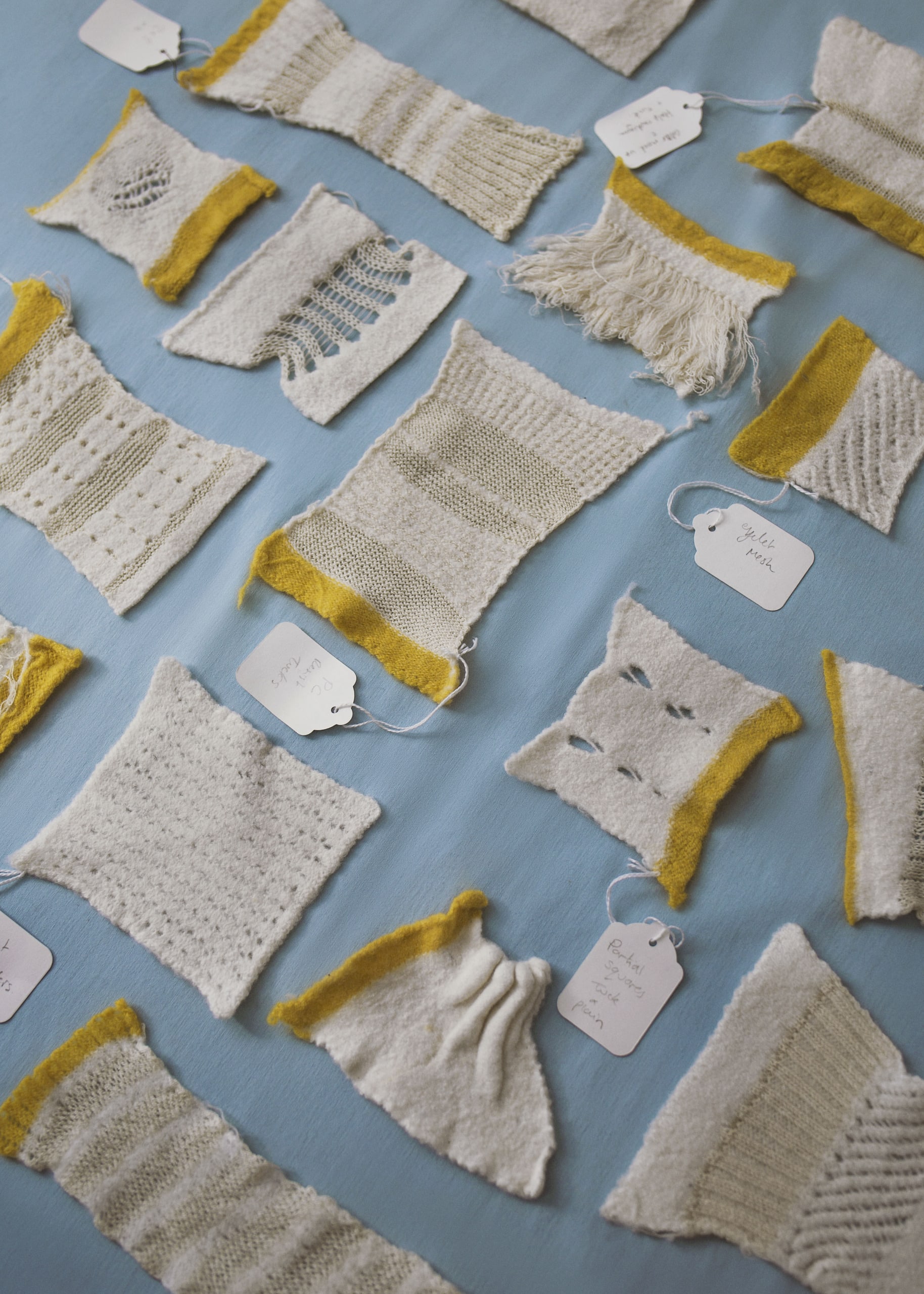 Selection of white knitted samples of different textures including holes, ladders, tassells