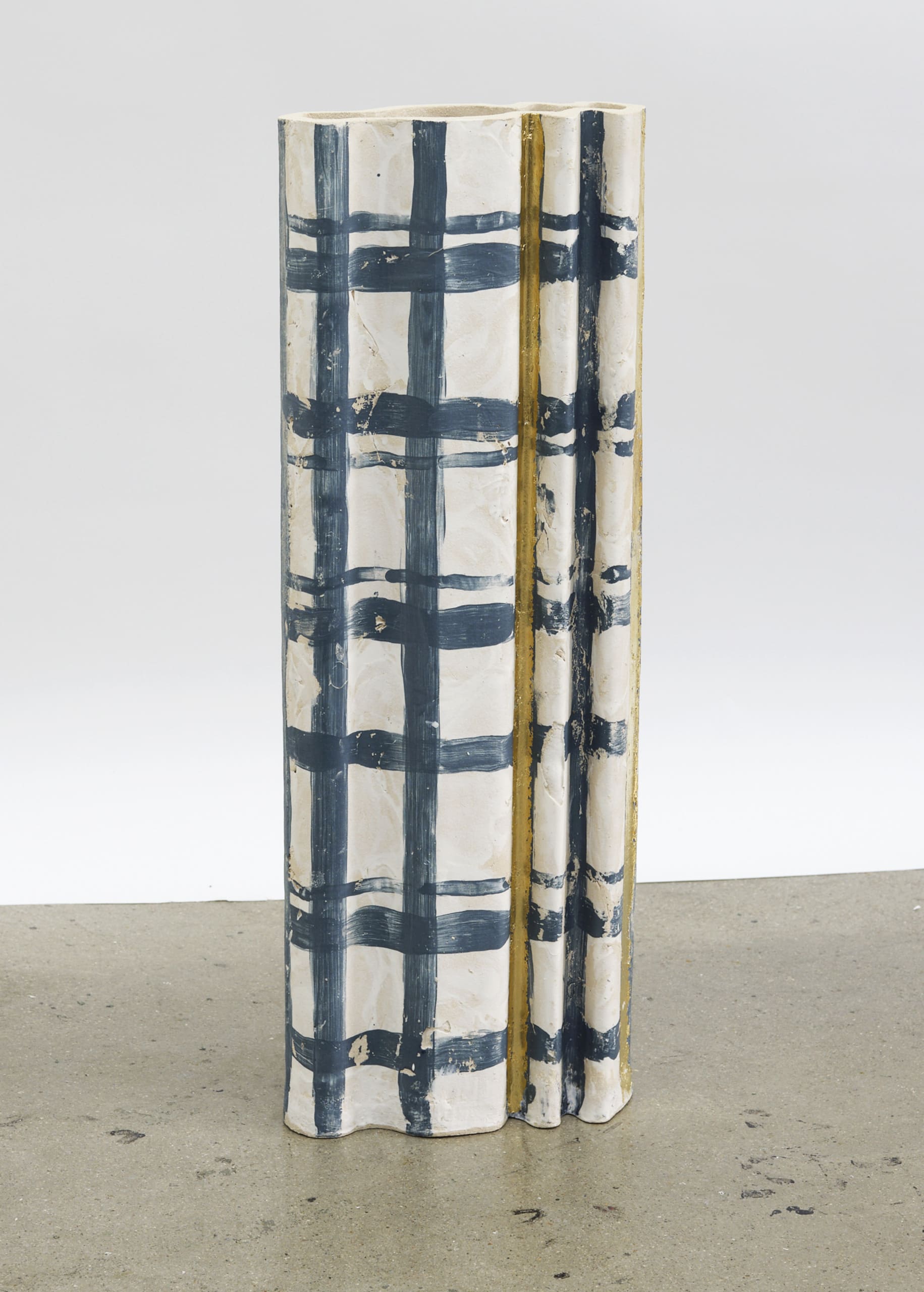 Tall vessels with a ripple form and a tartan pattern painted on in a navy blue. There is also gold leaf in some areas