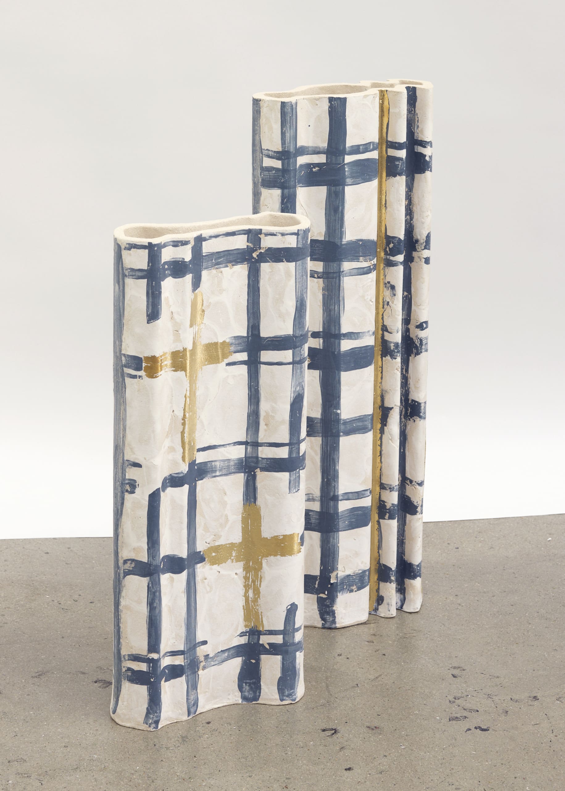 Two tall vessels. One taller than the other with navy tartan pattern gold leaf details
