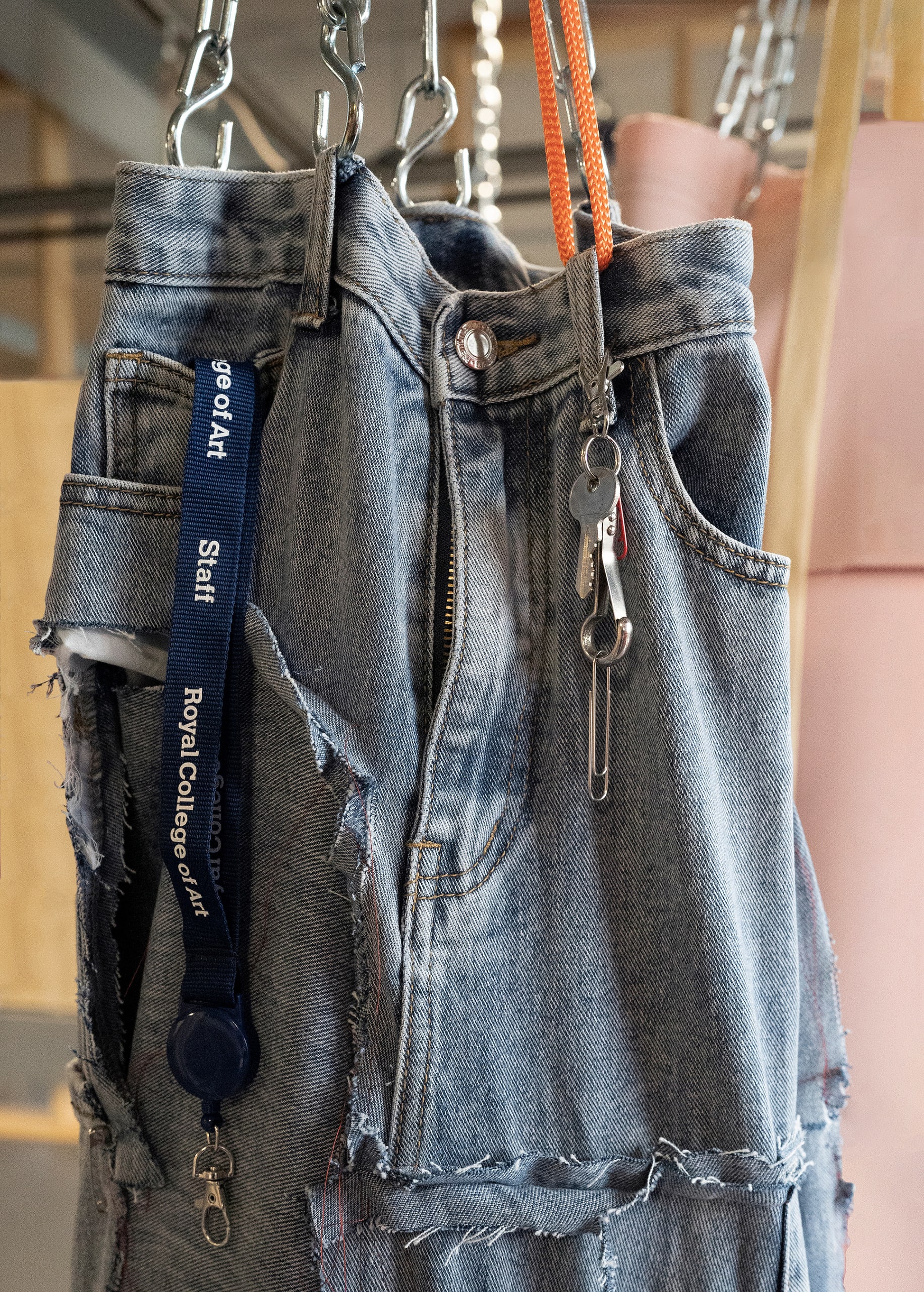 Close-up of hanging object made from waistband of blue jeans and hanging by metal chain with RCA Staff ID emerging from pocket