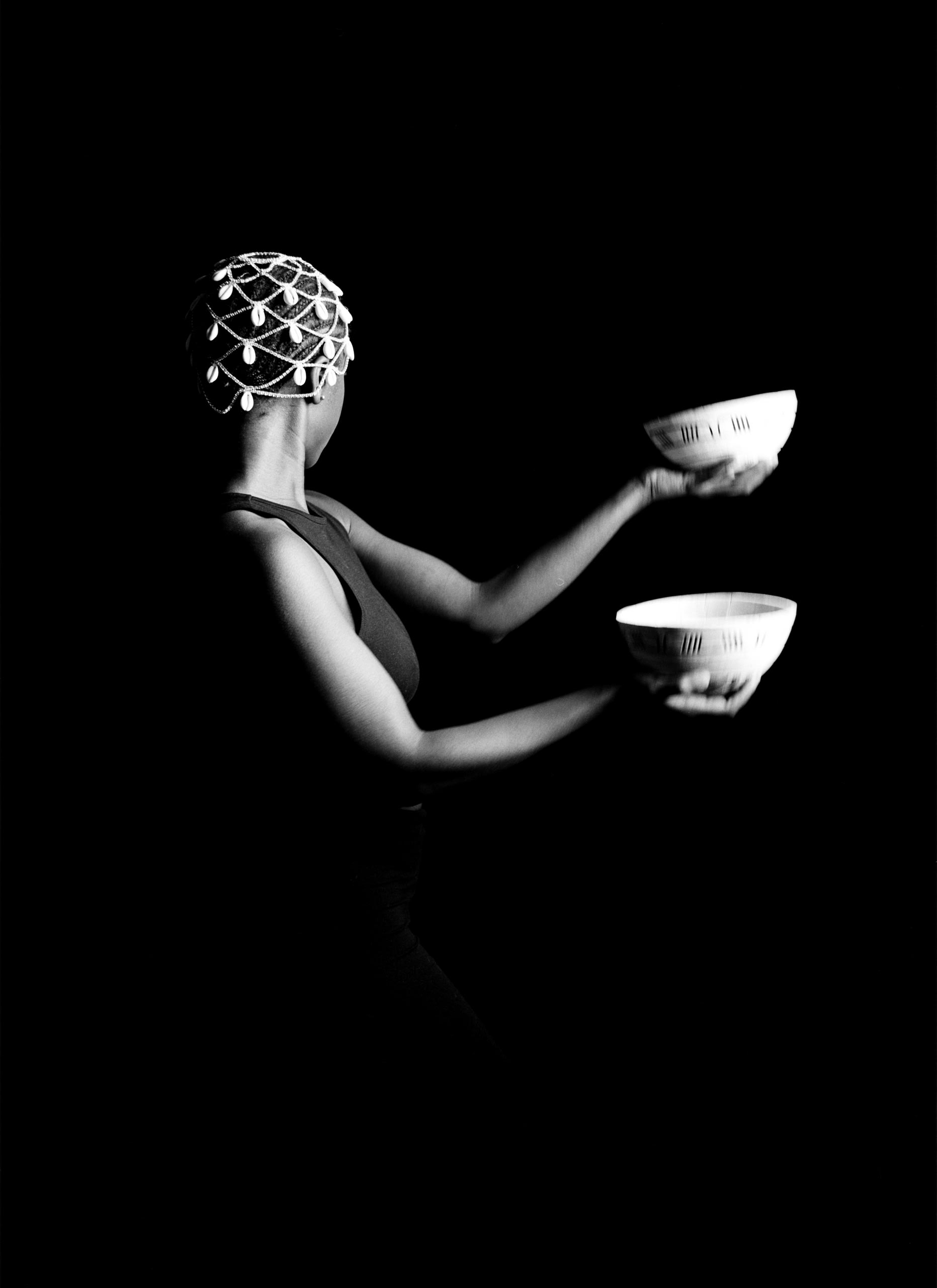 B and W image of girl throwing calabash looking behind 