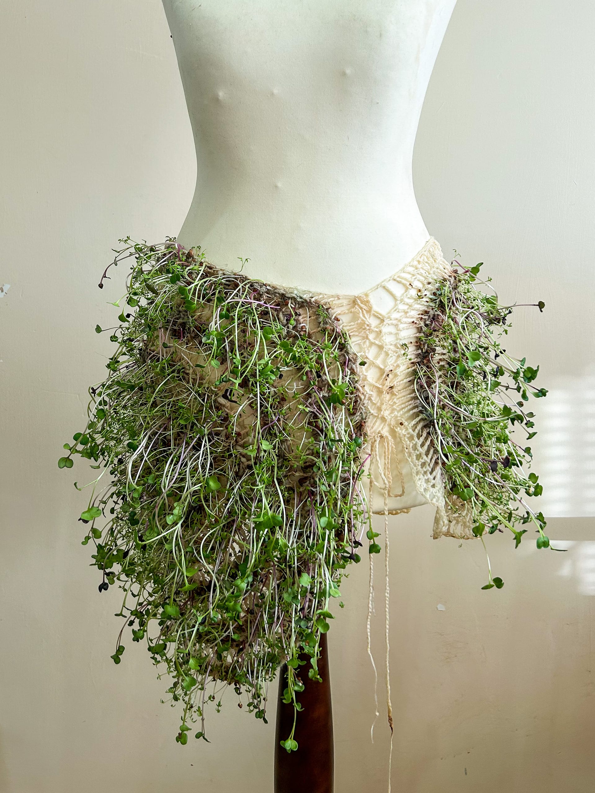 Uzumaki Skirt: asymmetric living crochet skirt on bottom of draw stand, face on against plain background
