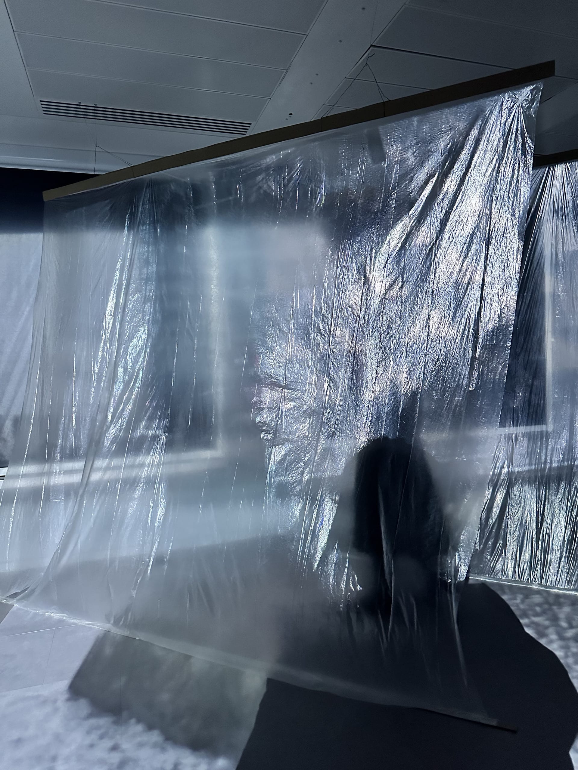 Installation in situ, depicts transparent sheets and a human shadow in the lower right hand corner